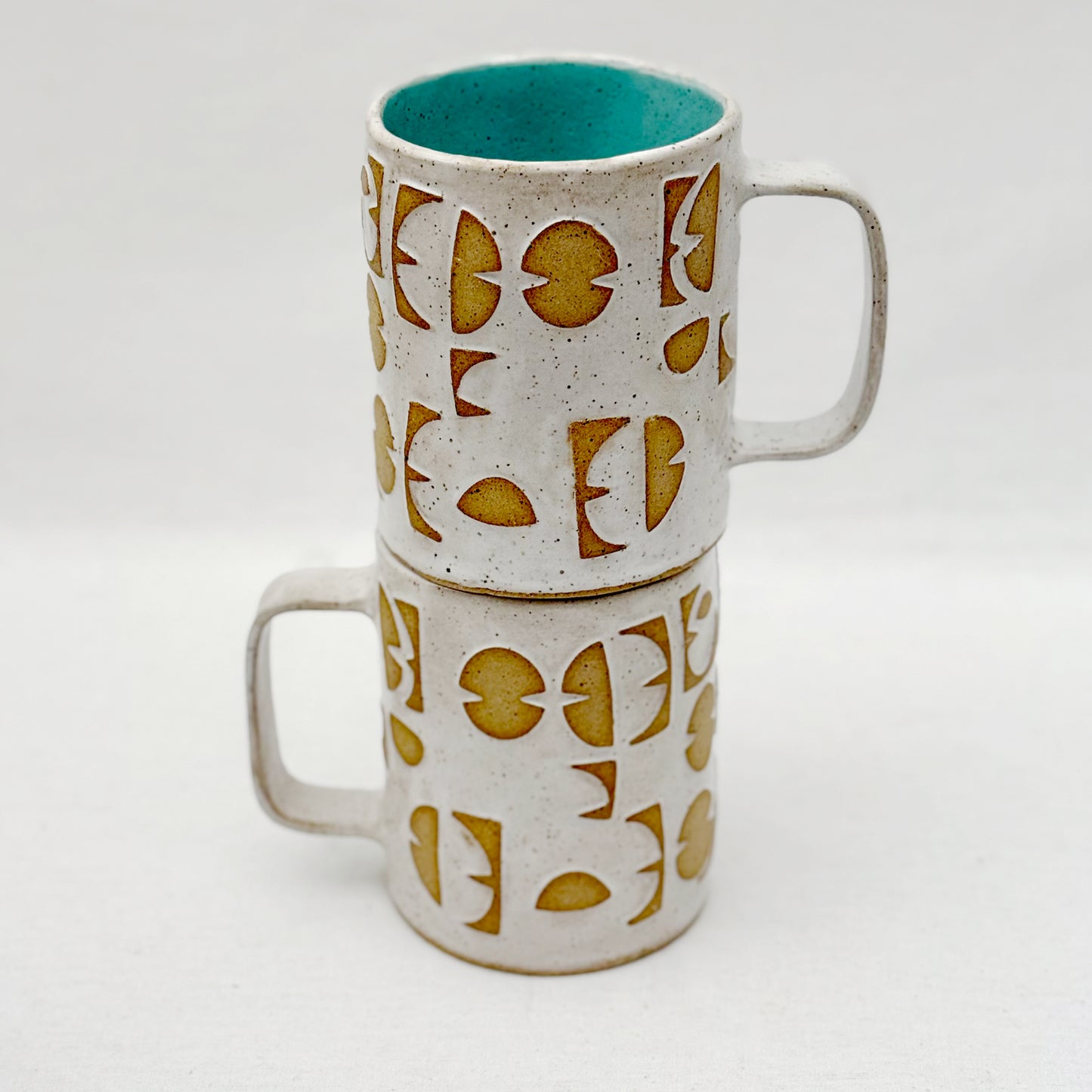 Stack of two ceramic mugs with geometric pattern on a white background