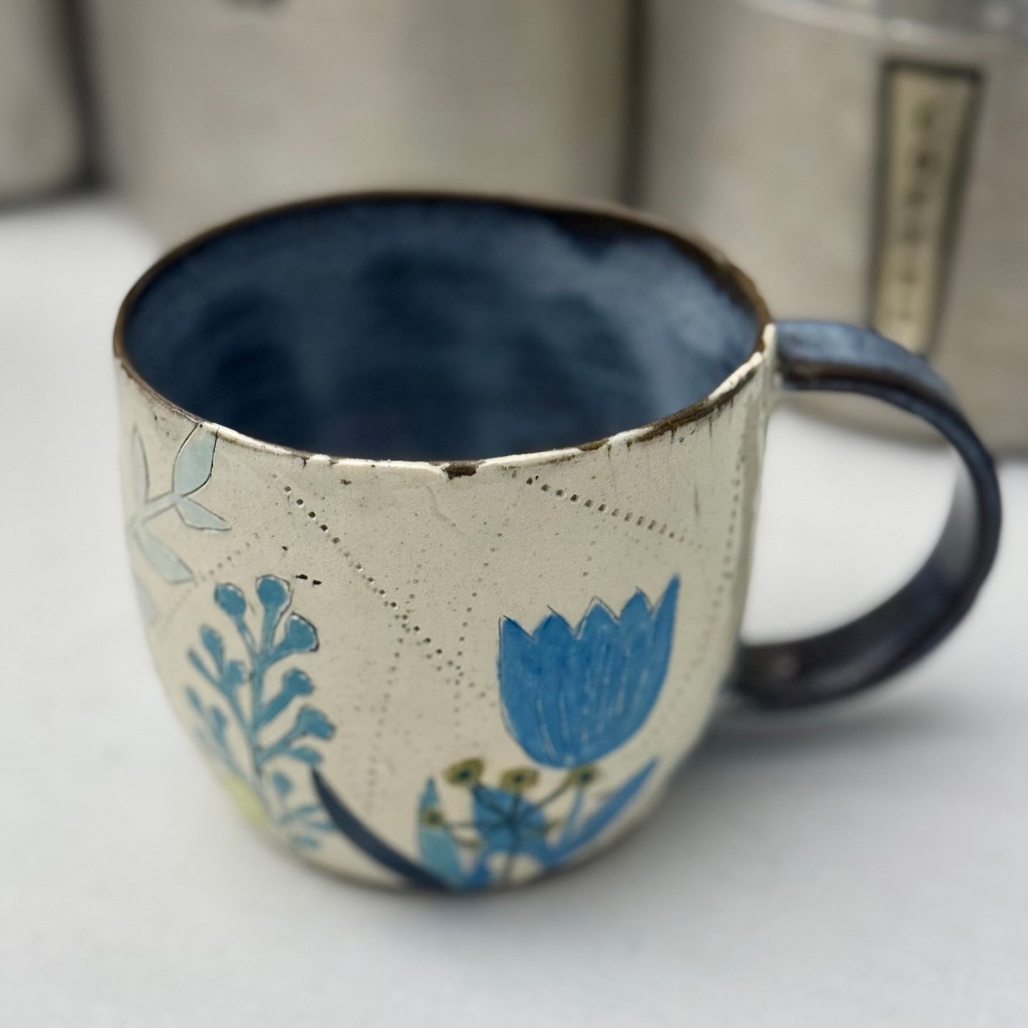 Ceramic mug with blue and green floral design on a white surface