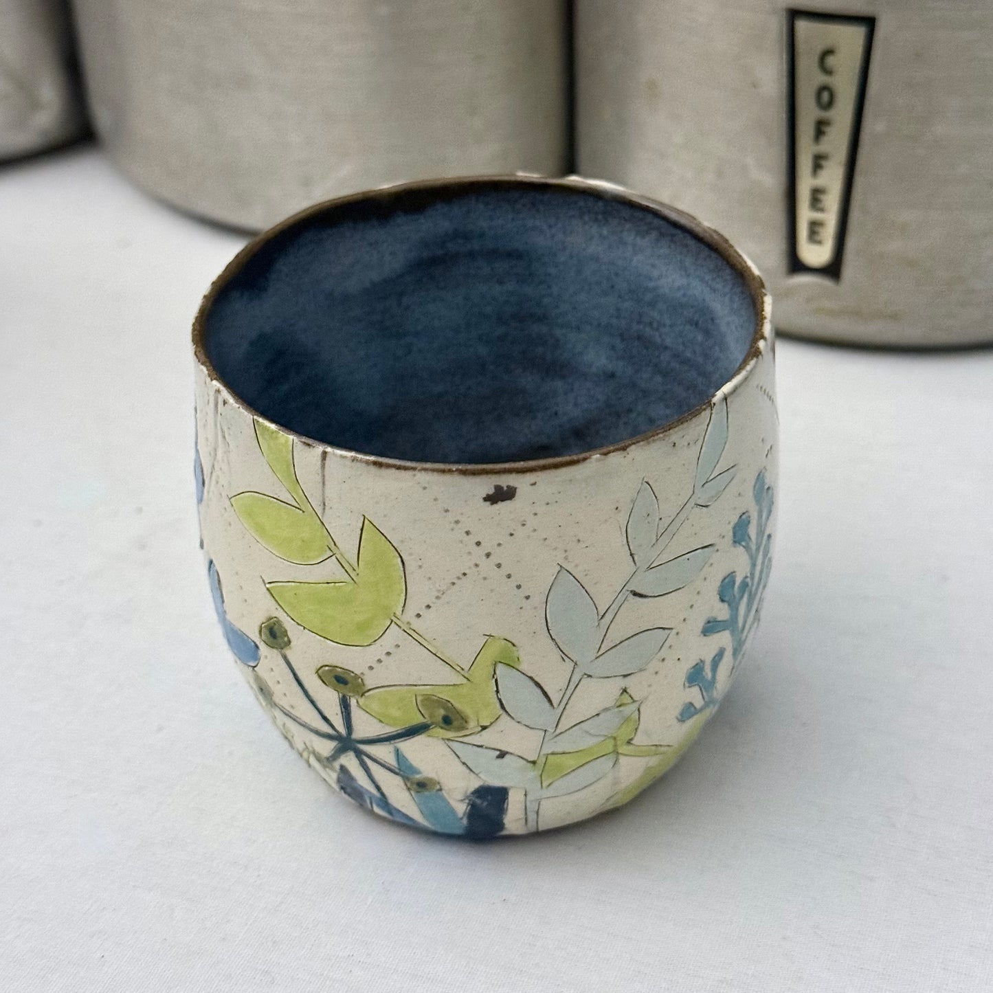 Ceramic mug with blue and green floral design on a white surface