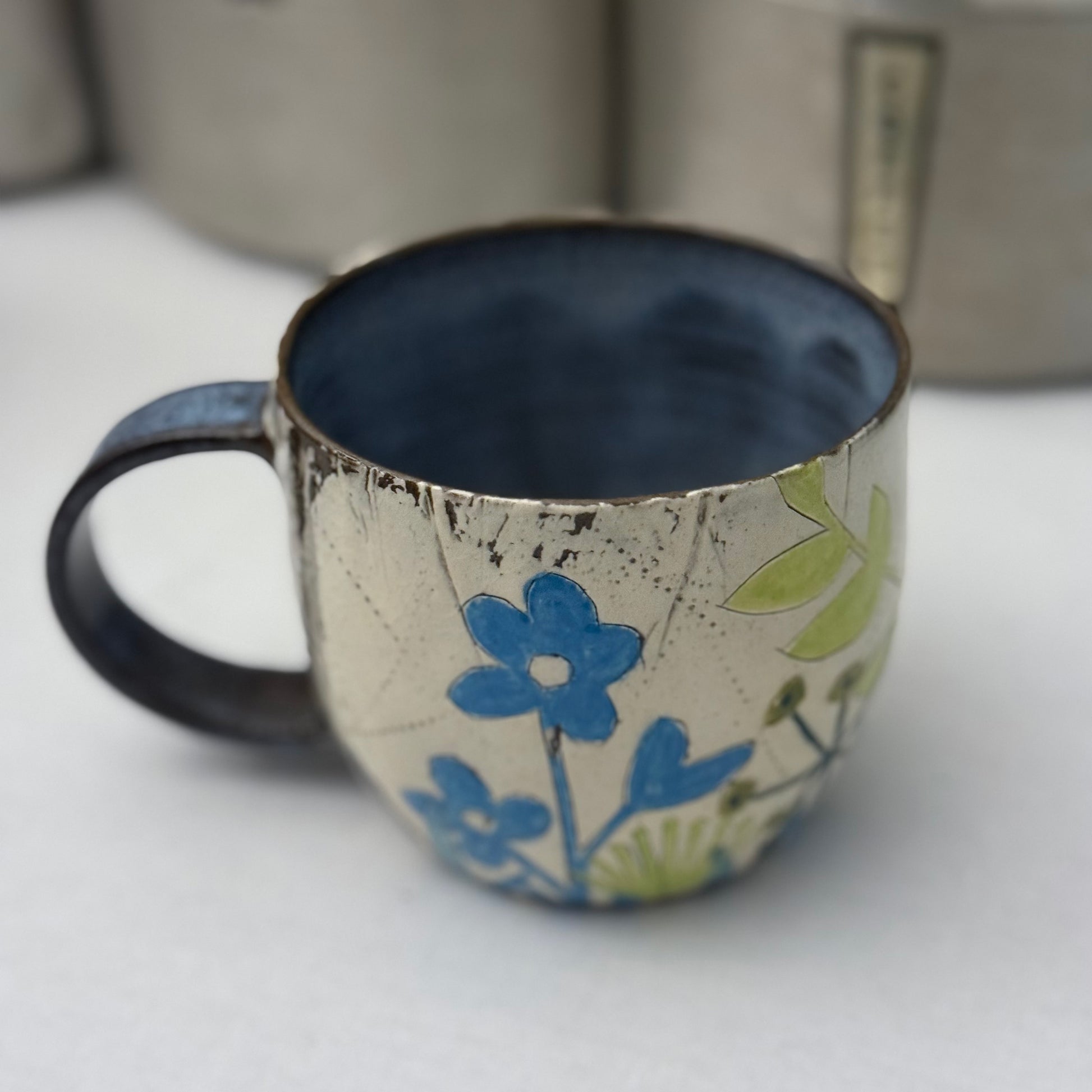 Ceramic mug with blue  and green floral design on a white surface