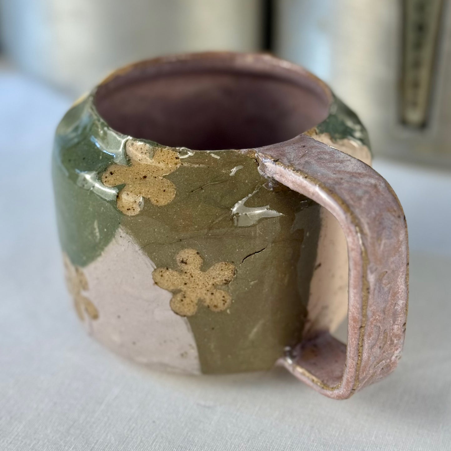 Handmade ceramic mug with floral patterns on a white surface