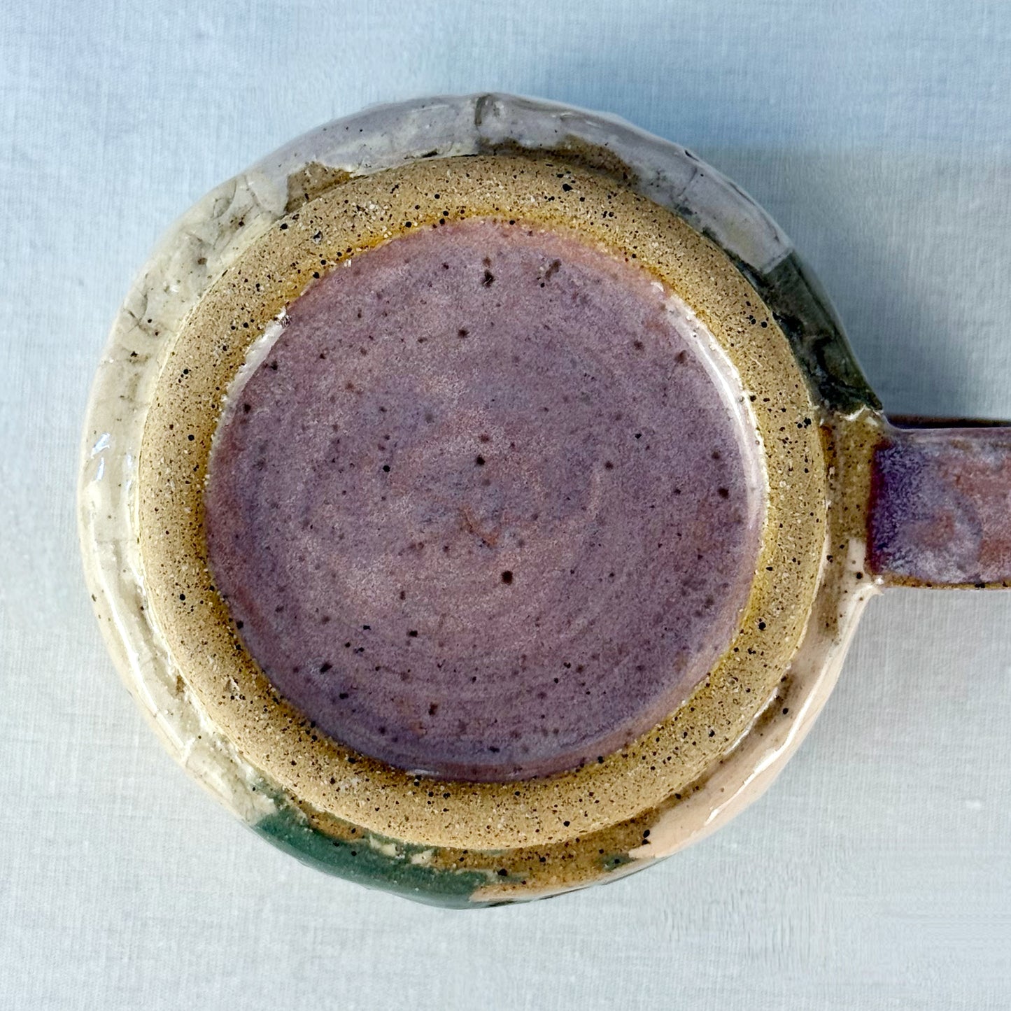 Close-up of bottom of ceramic mug with a textured surface on a light background