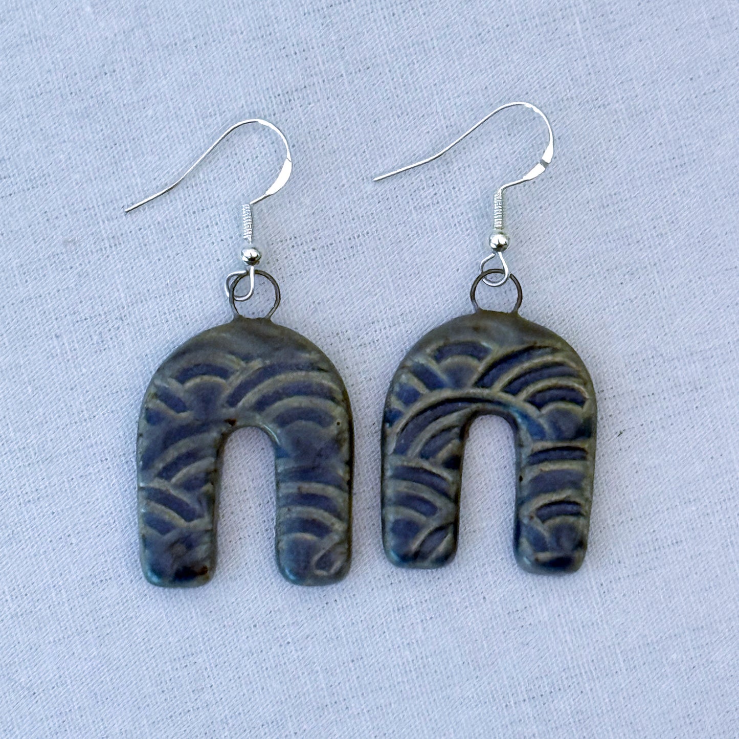 Pair of blue patterned earrings on a light blue background