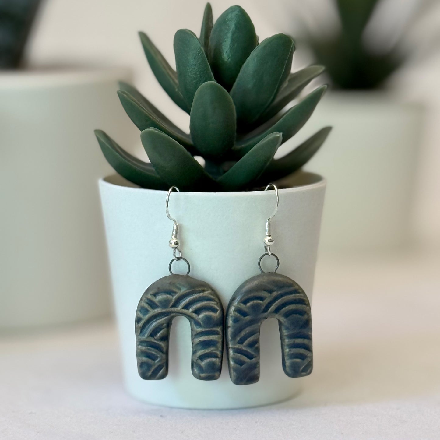 Pair of earrings with a plant in the background