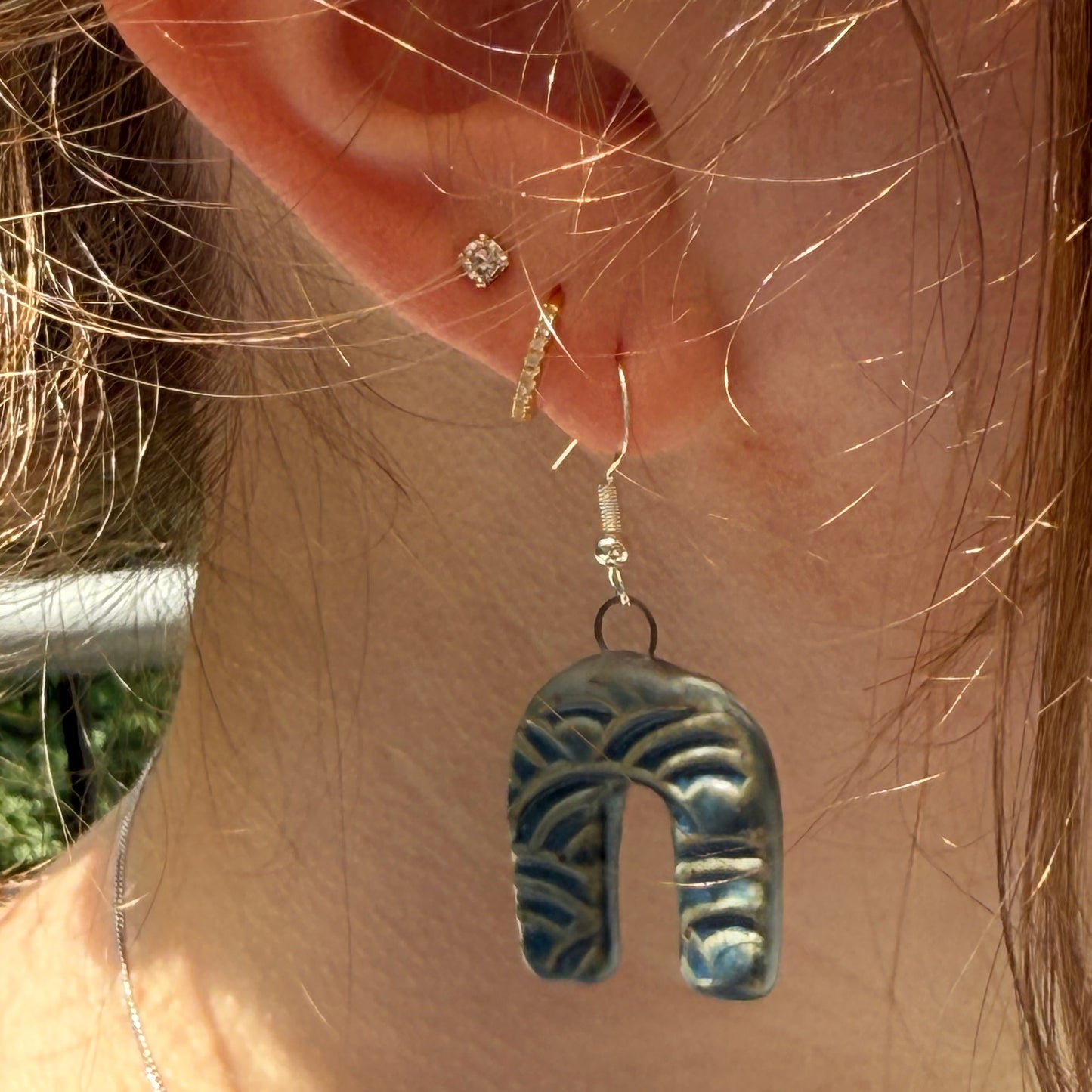 Close-up of an ear with a blue arch earring