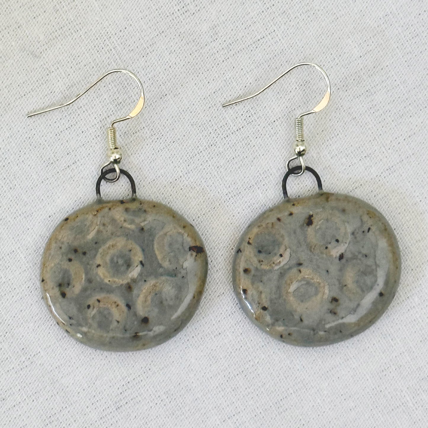 Pair of ceramic earrings with decorative patterns on a light background