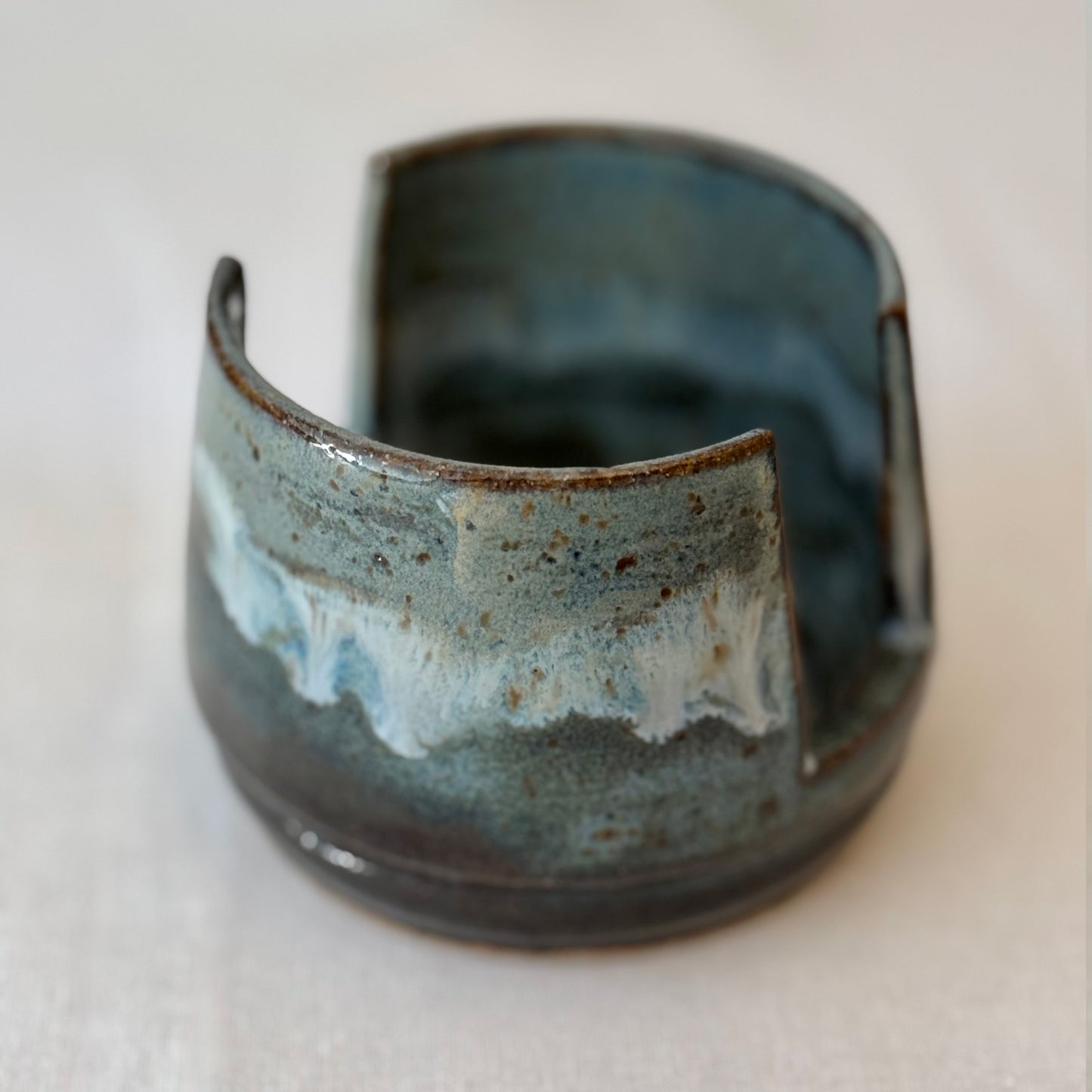 Ceramic sponge holder with blue and brown glaze on a neutral background