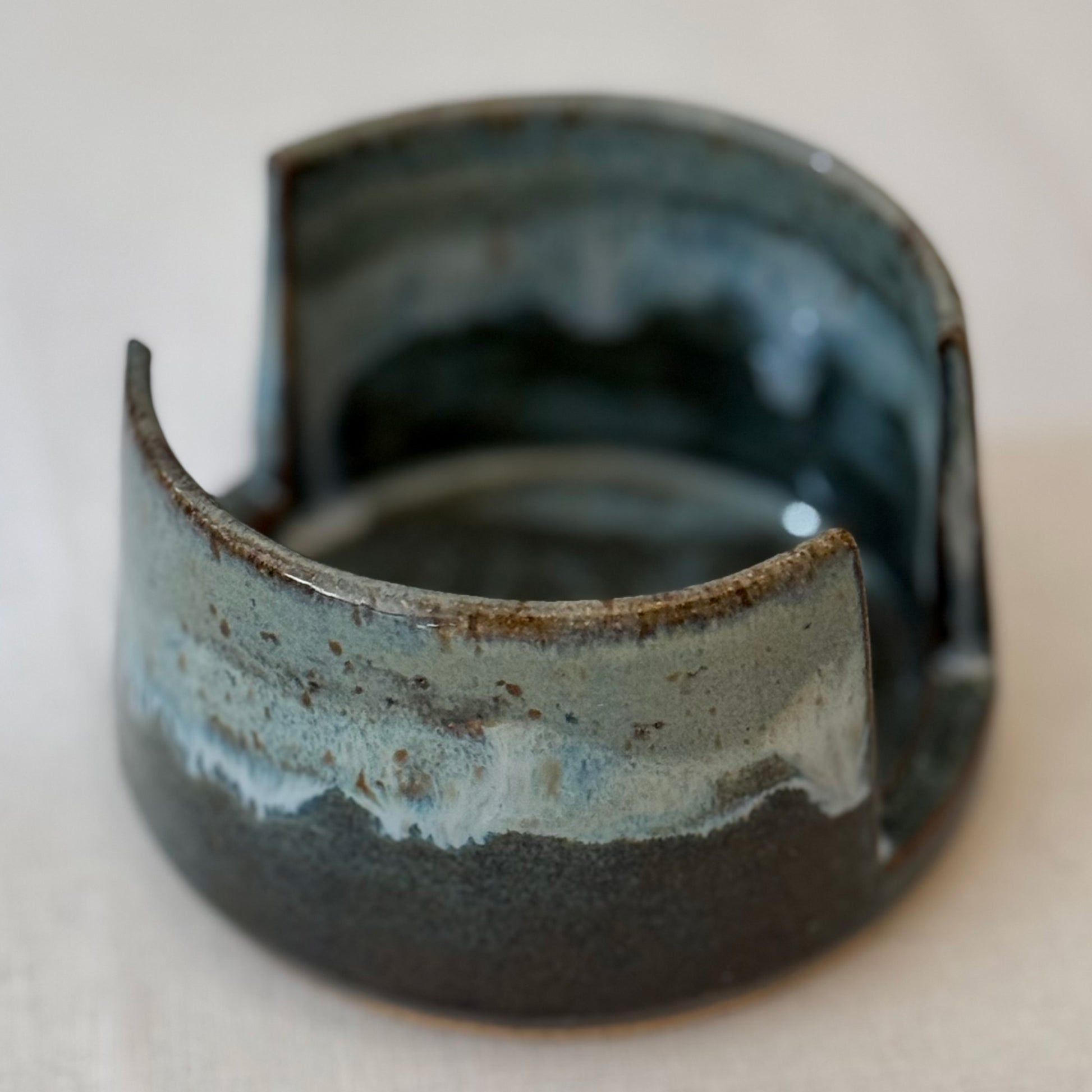 Ceramic sponge holder with blue and brown glaze on a neutral background