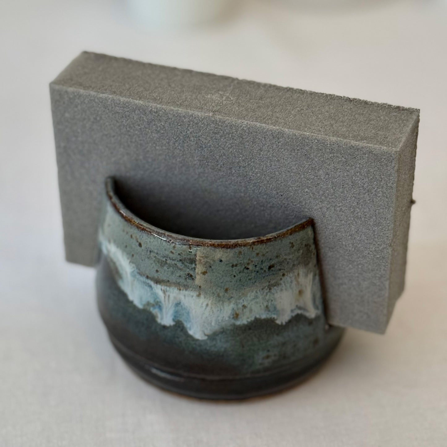 Ceramic sponge holder with blue and brown glaze on a neutral background