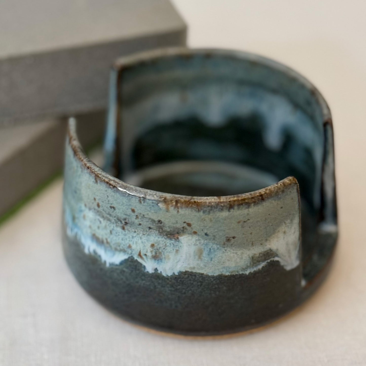 Ceramic sponge holder with blue and brown glaze on a neutral background