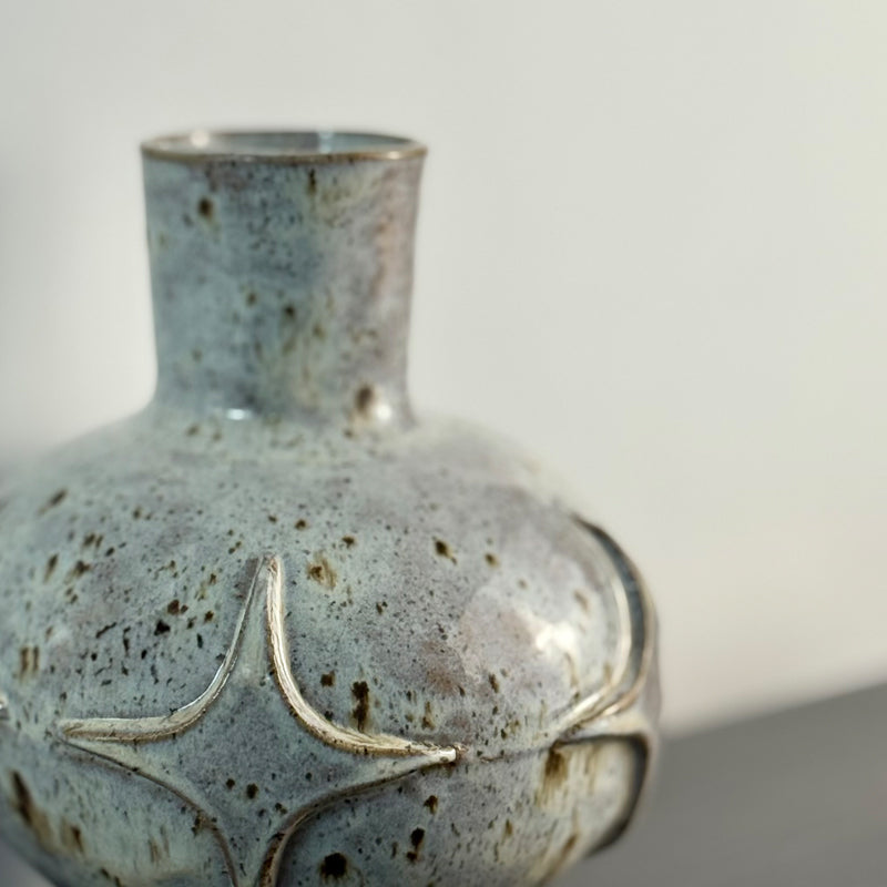 Handcrafted ceramic bud vase with a carved mid-century modern starburst pattern and warm speckled ivory glaze.