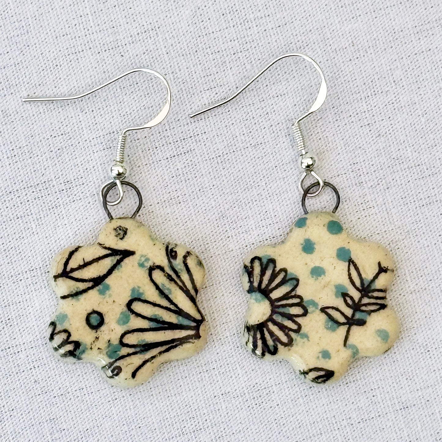 Pair of floral-patterned earrings on a light fabric background