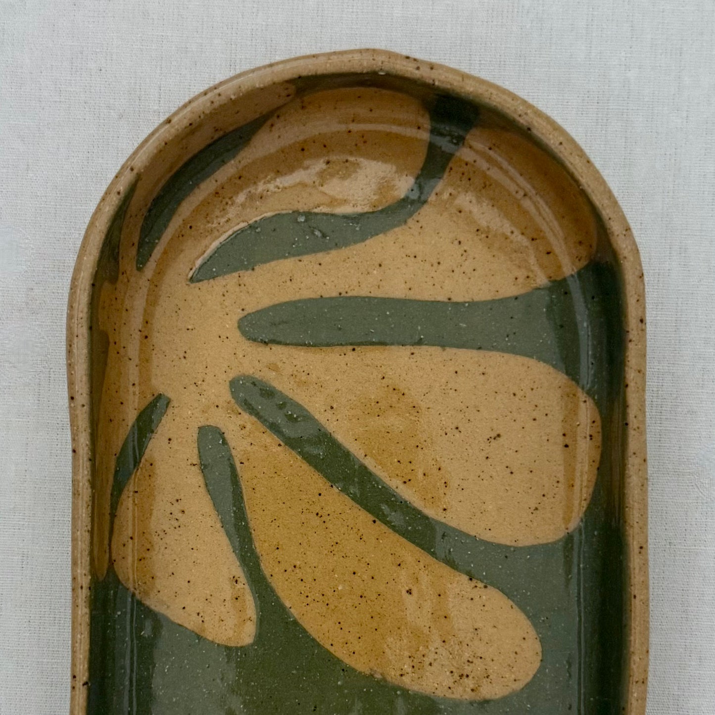 Ceramic dish with leaf design on a light gray background