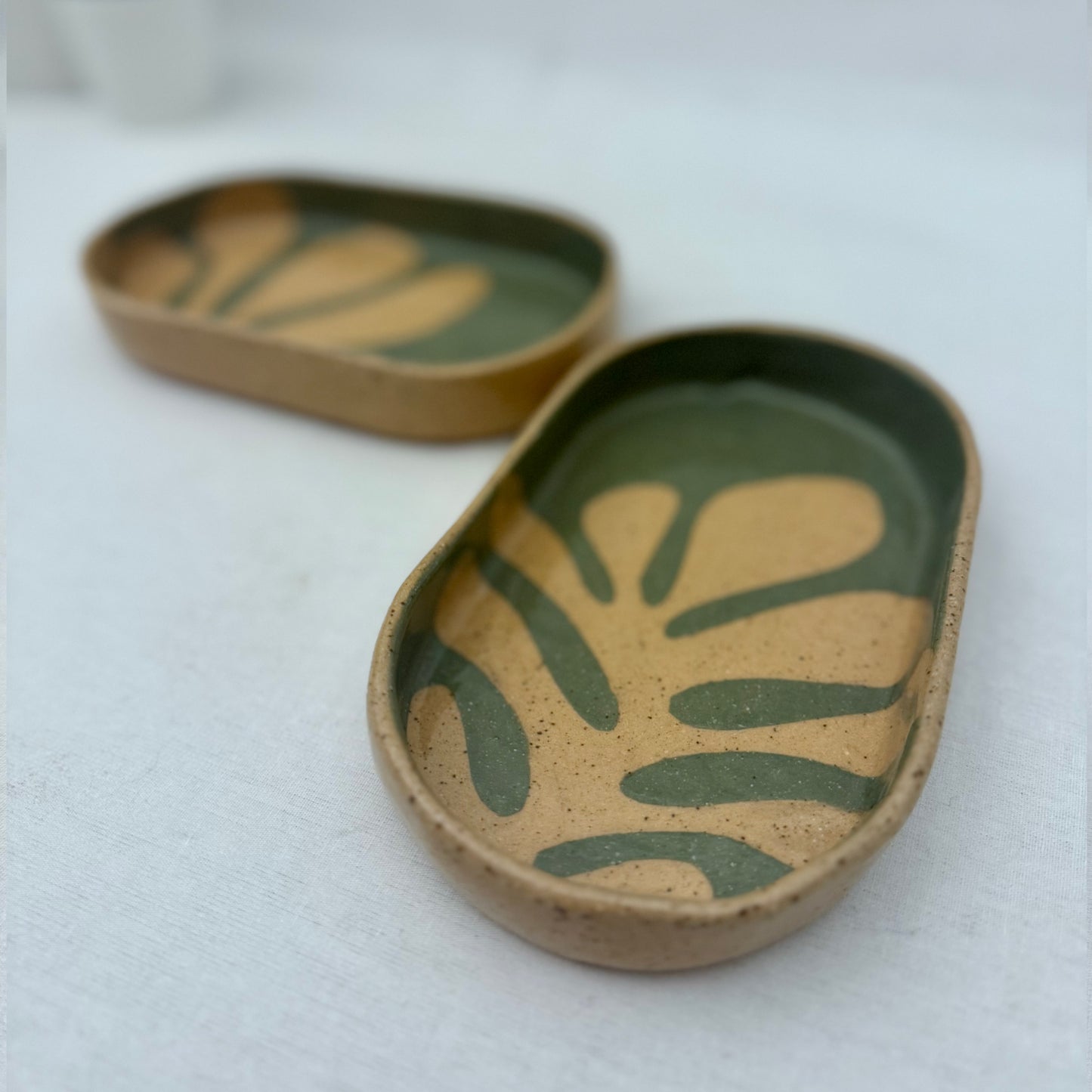 Two ceramic trays with leaf patterns on a white background