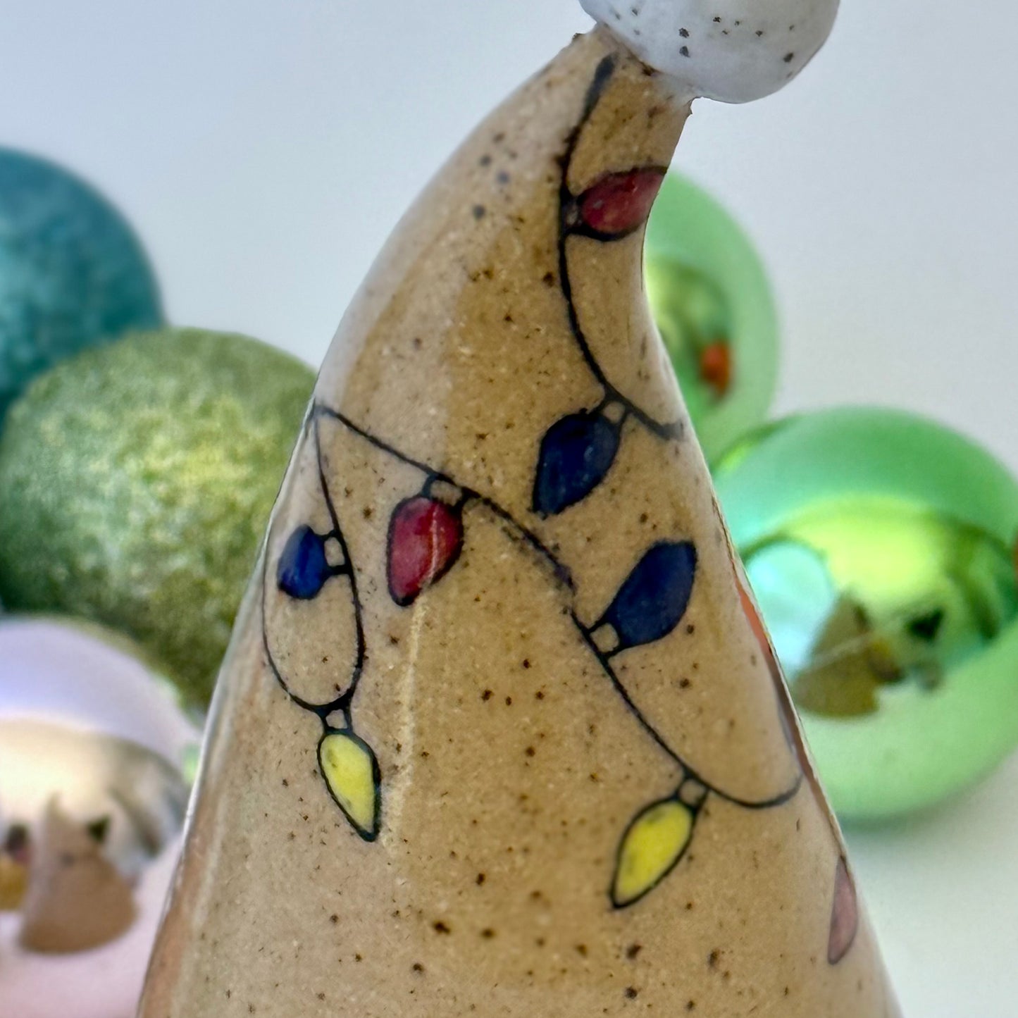 close-up of ceramic gnome with holiday lights with ornament on a white background