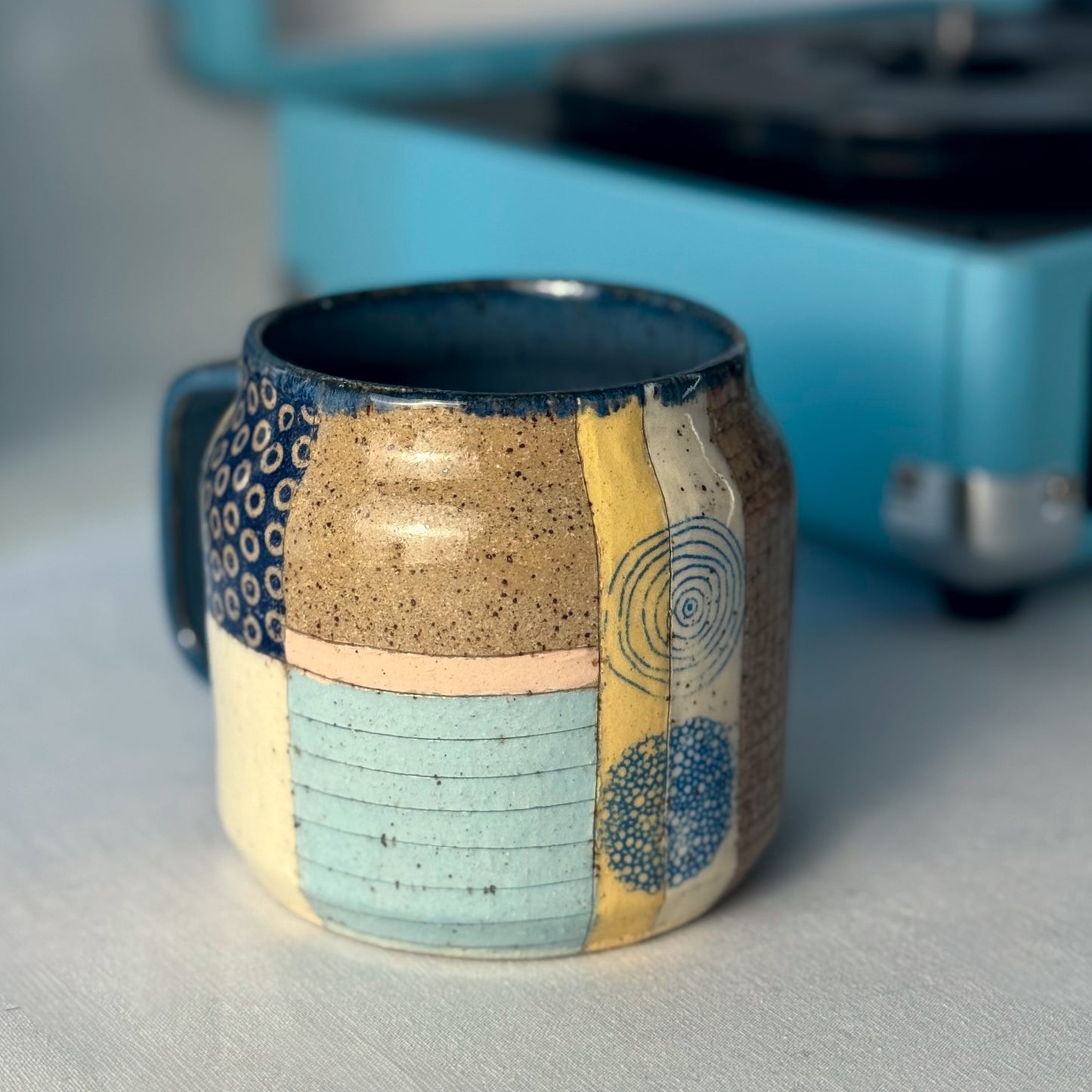 Ceramic mug with multicolored patterns on a gray surface with a blurred background