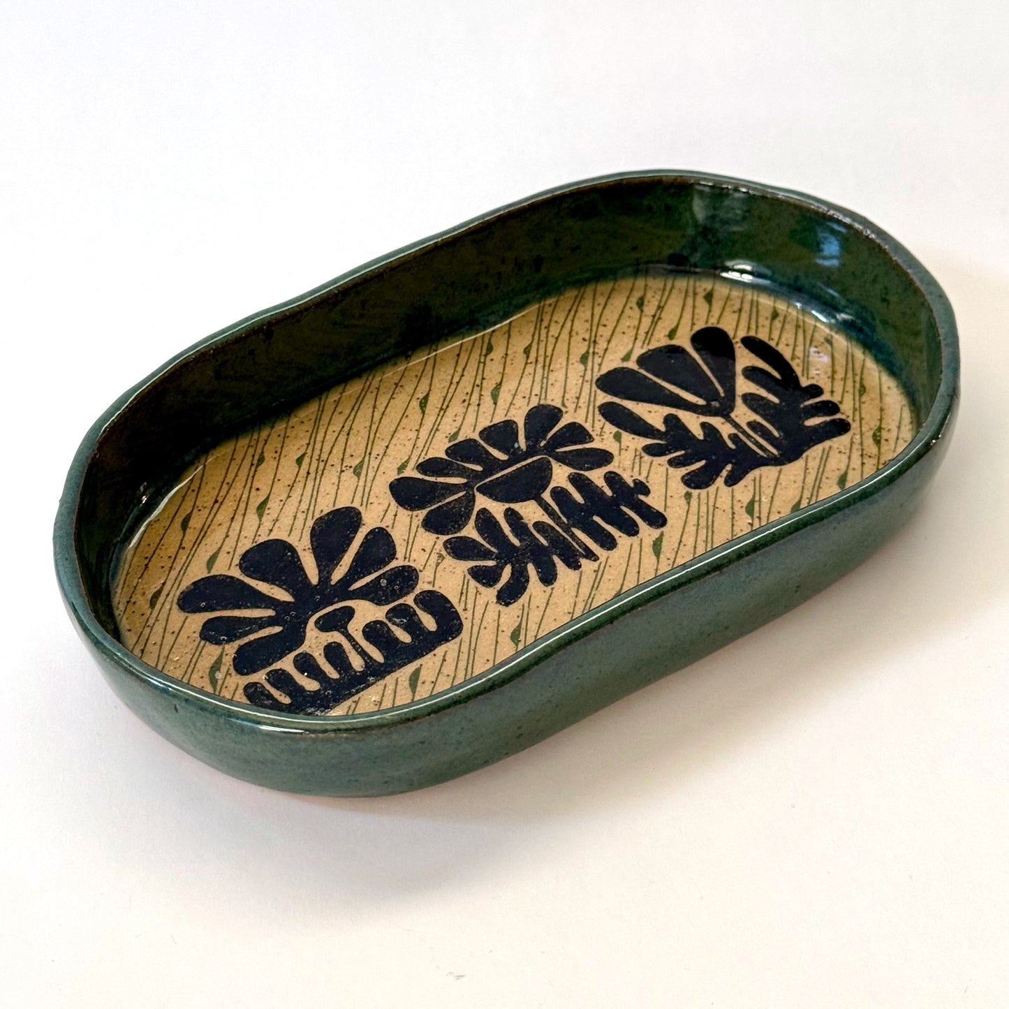 Ceramic dish with black floral patterns on a beige background