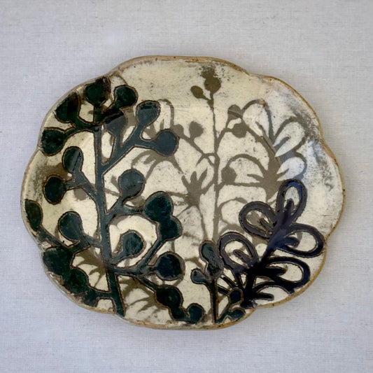 Ceramic plate with dark teal floral design on a white background