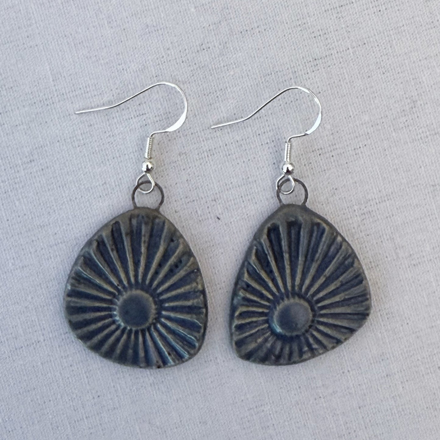 Pair of earrings with sunburst design on a light gray background