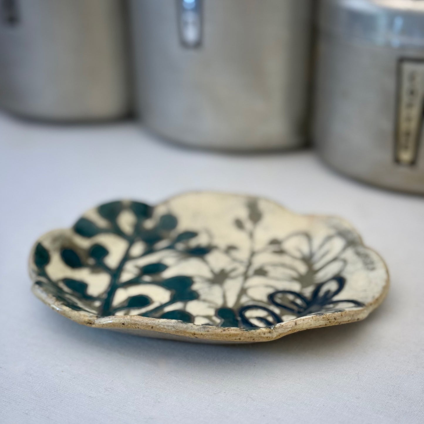 Ceramic plate with dark teal floral design on a white background