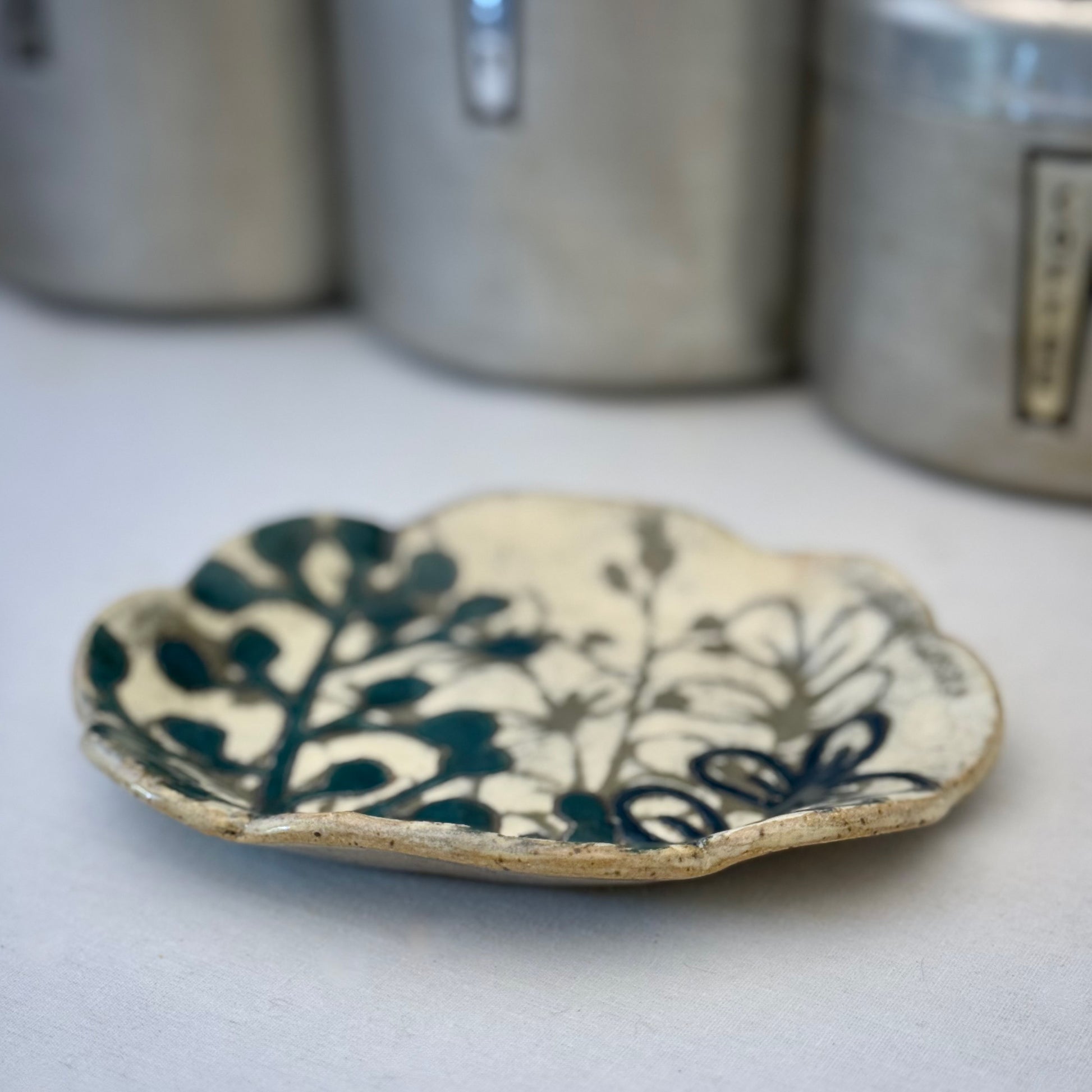 Ceramic plate with dark teal floral design on a white background