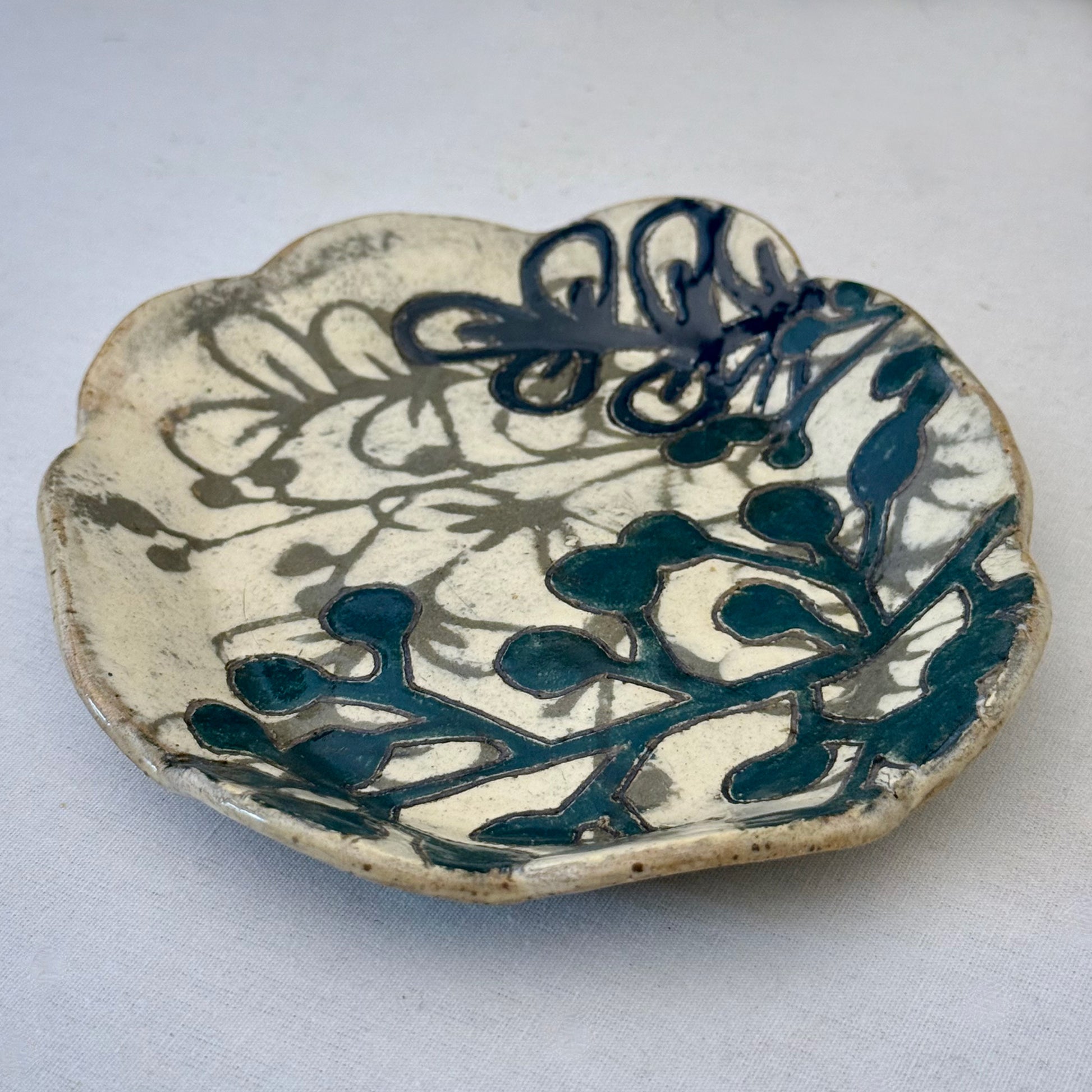 Ceramic plate with dark teal floral design on a white background