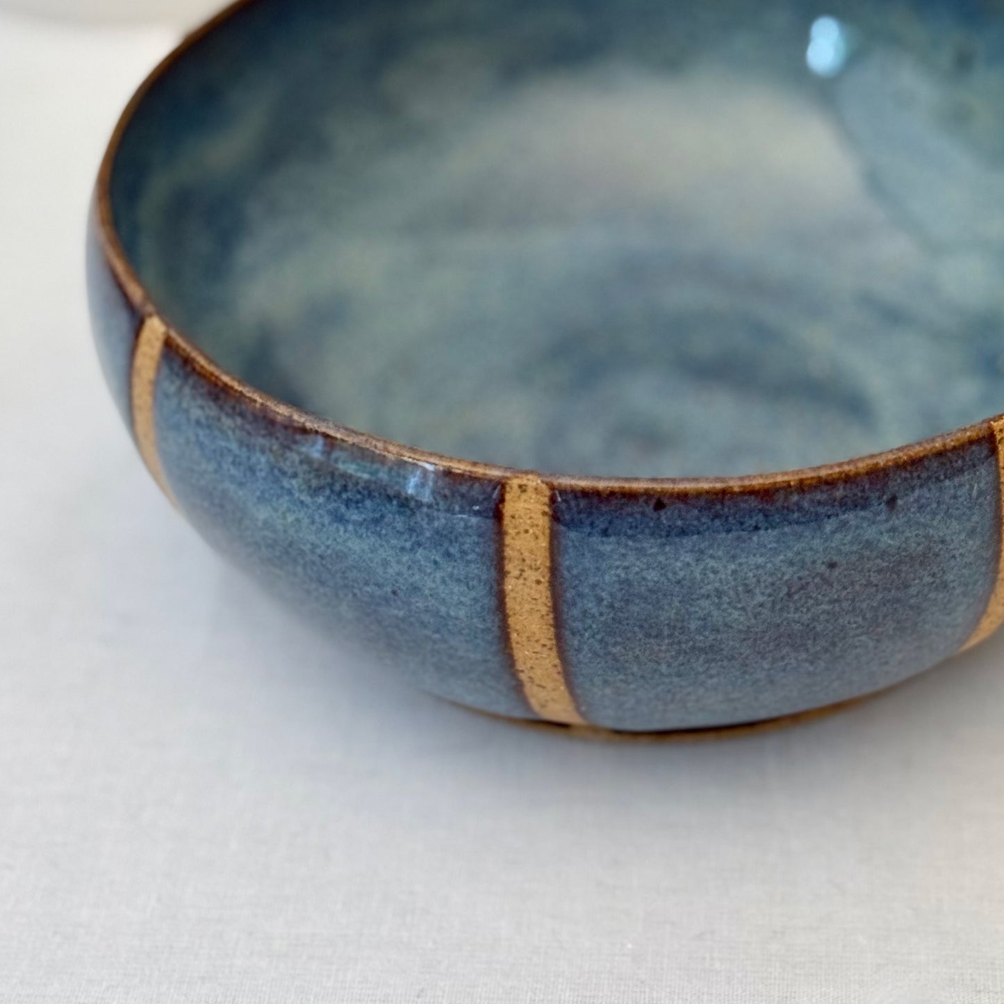 Blue ceramic bowl with natural clay accents on a white background