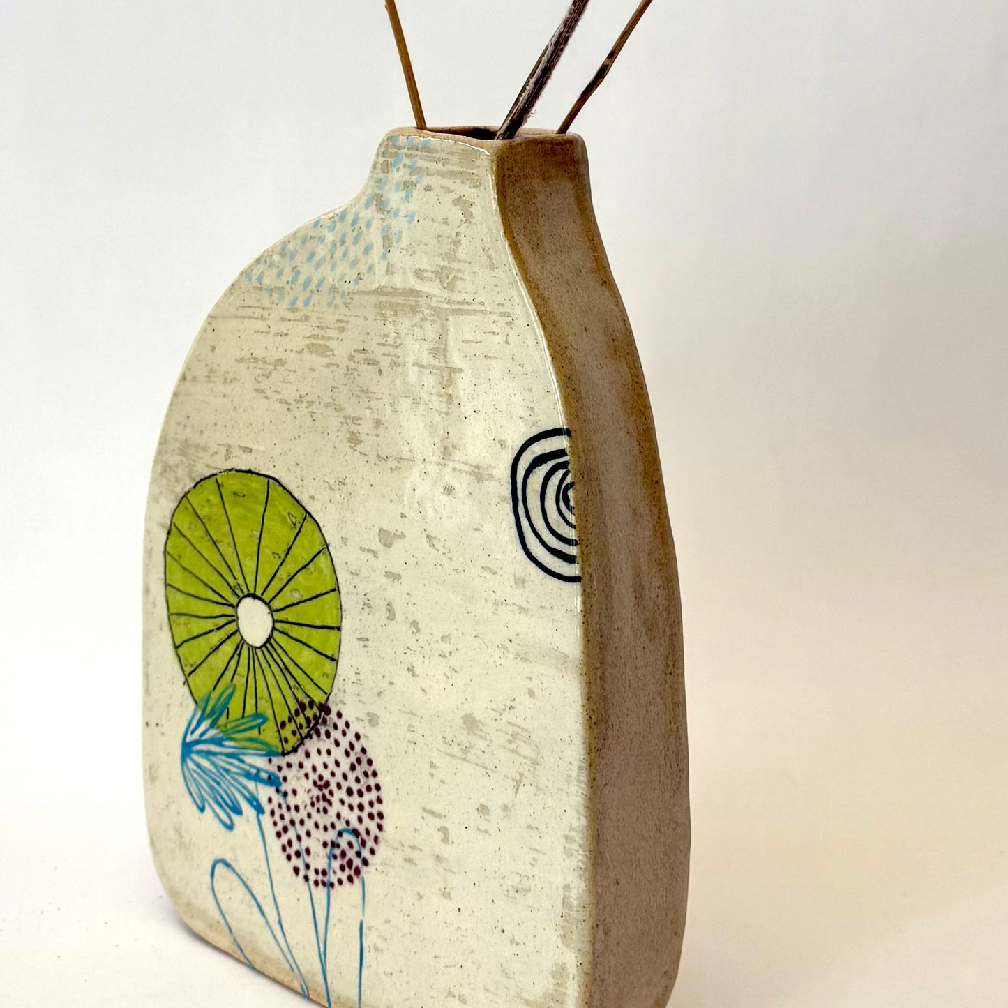 Handmade ceramic vase with a rounded form, featuring two different hand-drawn illustrated designs on opposite sides, photographed on a neutral background.