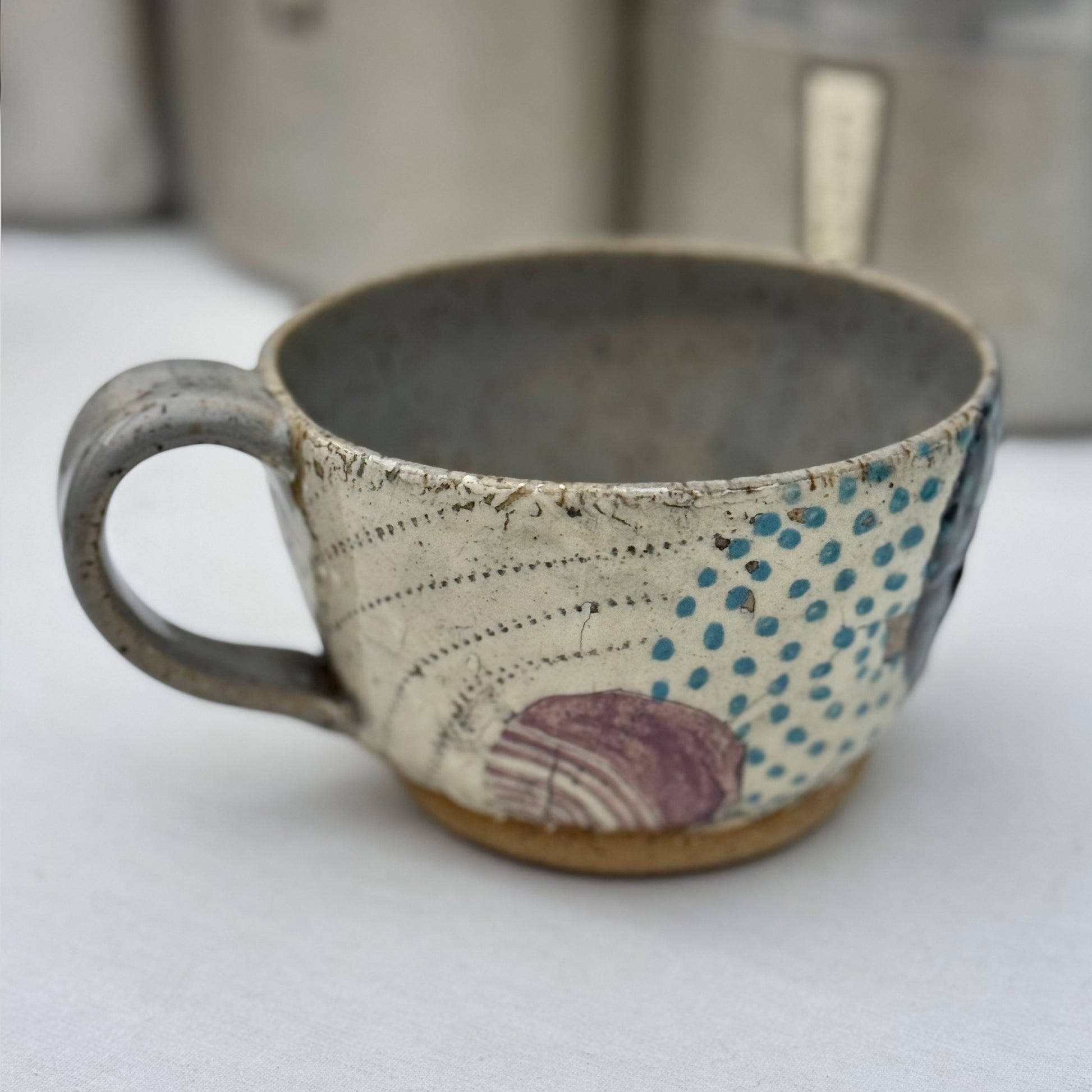 Ceramic mug with textured surface and colorful patterns on a white background