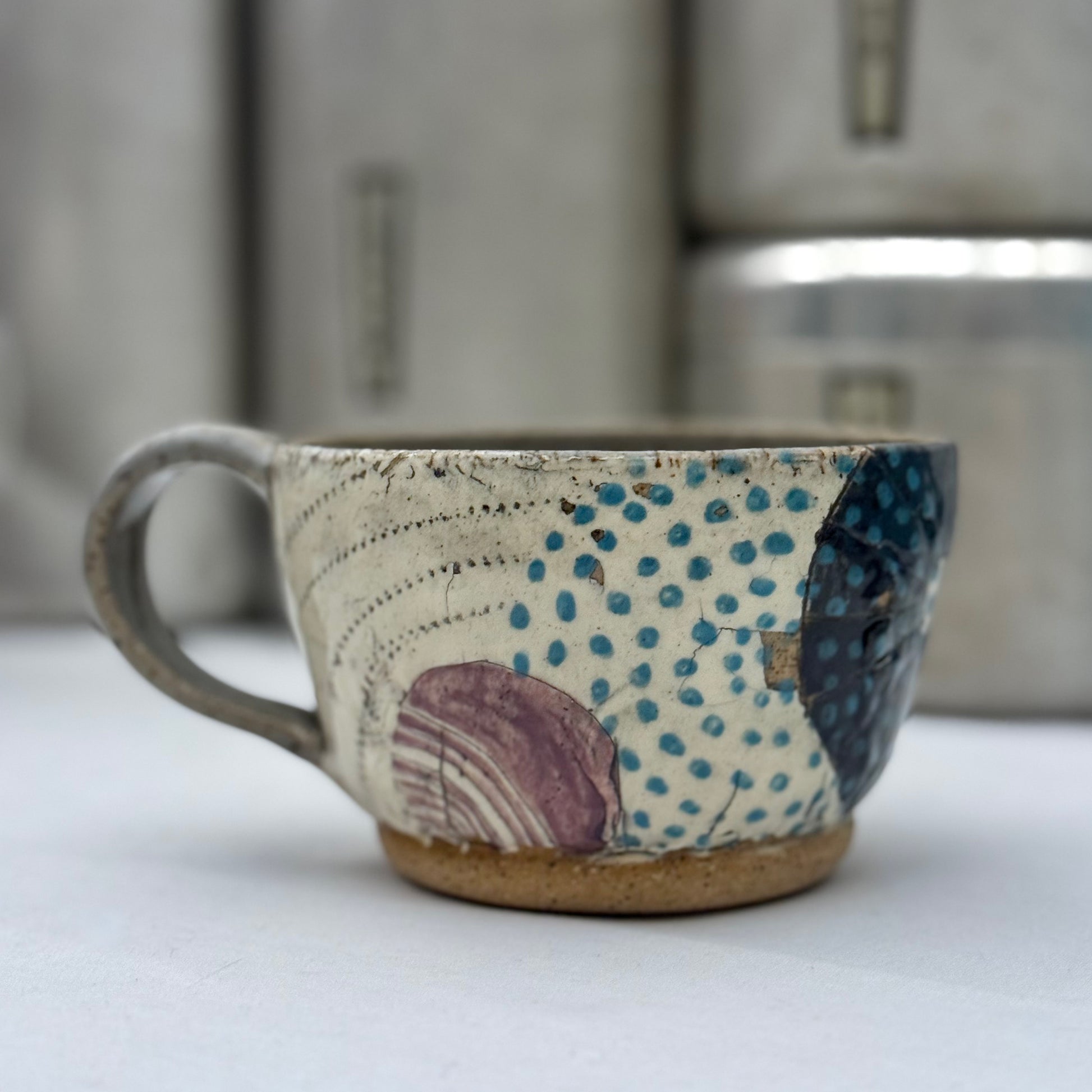 Ceramic mug with textured surface and colorful patterns on a white background