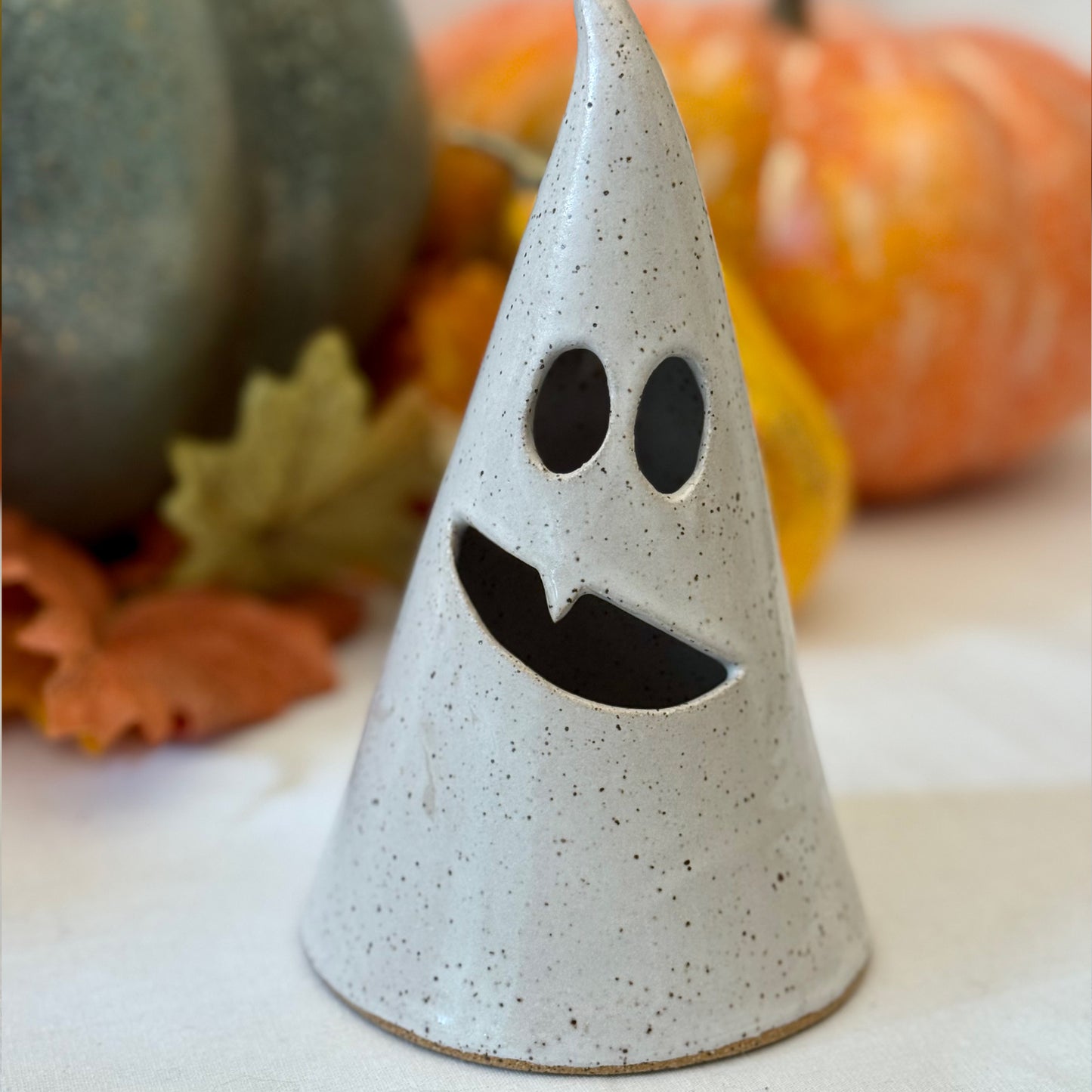 large white ceramic luminary with pumpkins and leaves in the background