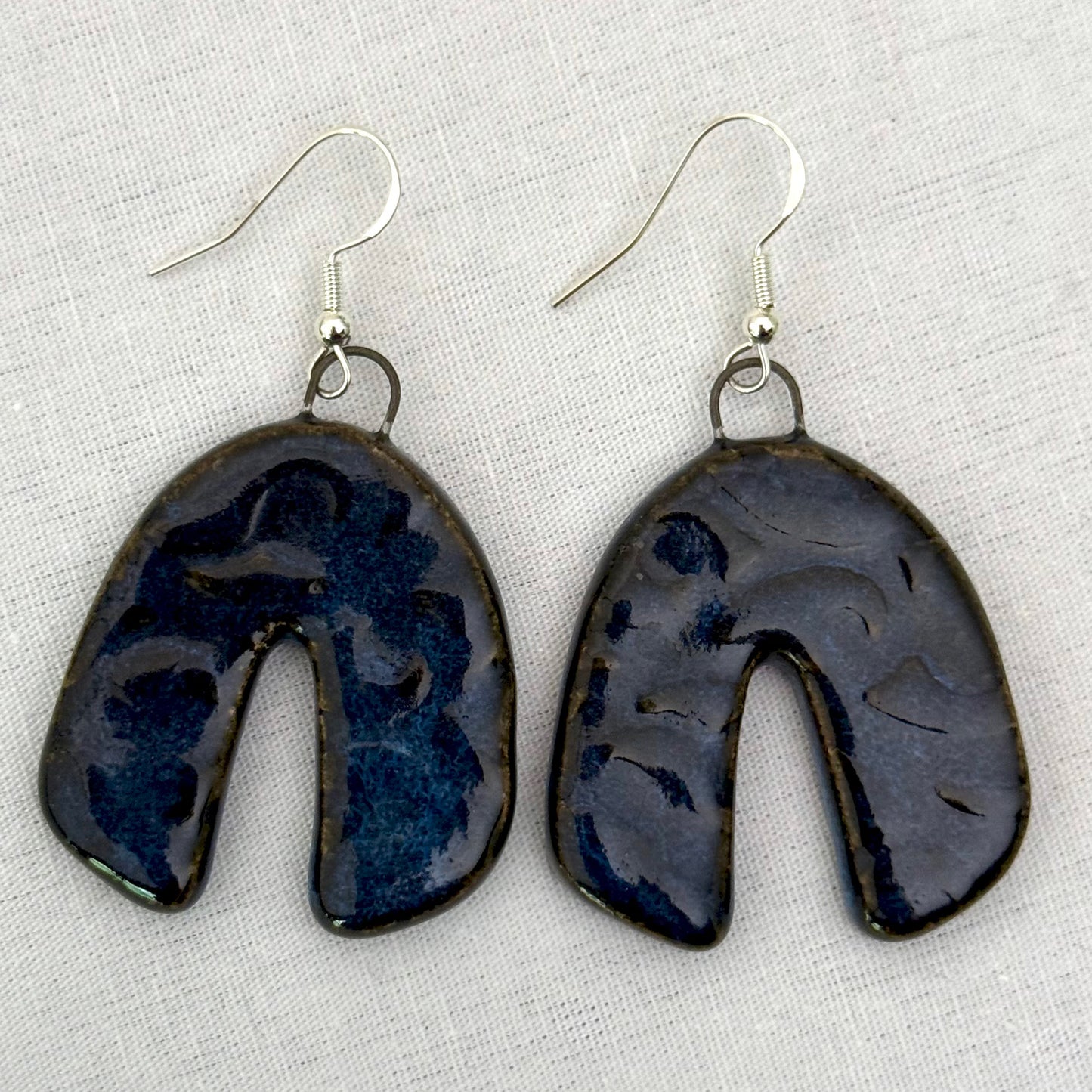 Pair of dark blue ceramic earrings on a light background