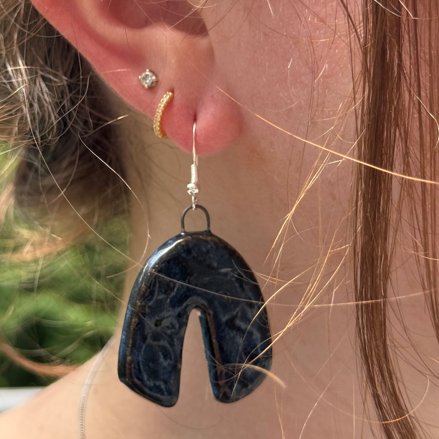 Close-up of a person wearing a blue textured earring with a blurred background