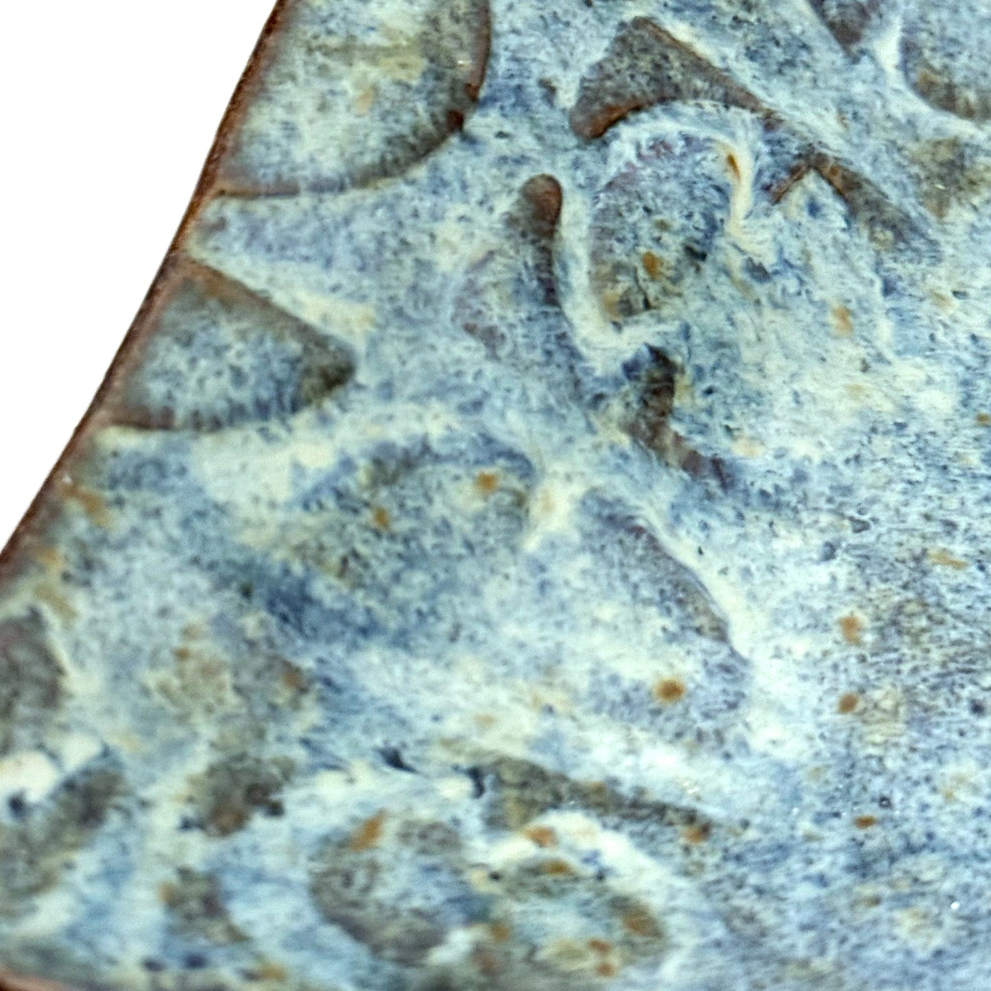 Close-up of hand built stoneware tray with an impressed repeating mid century inspired pattern and layered blue glaze.
