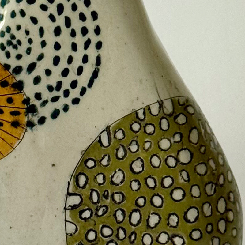 Close up of handbuilt speckled stoneware vase with colorful mid-century-inspired monoprints featuring graphic florals, dotted orbits, and botanical motifs, finished in a glossy clear glaze