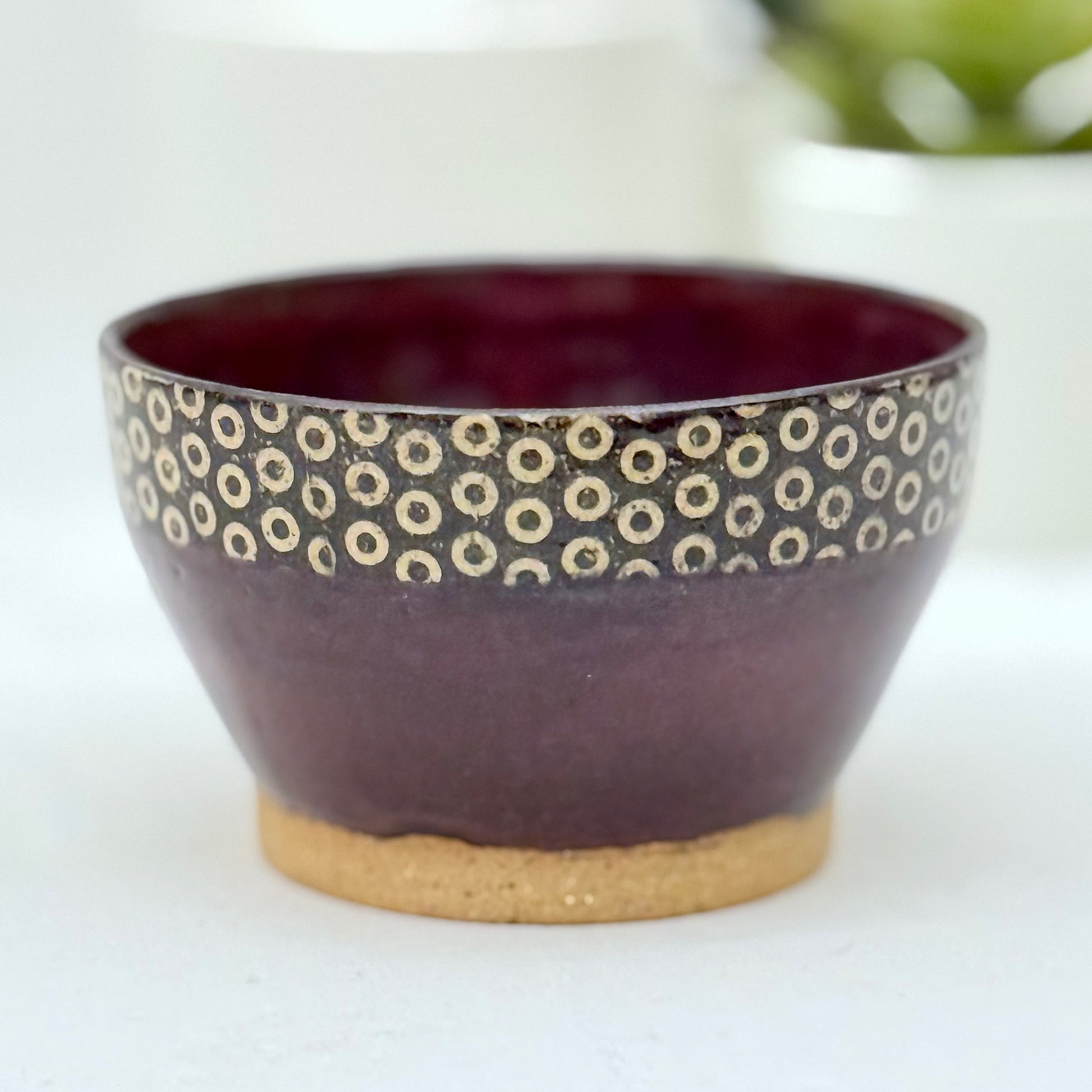 Ceramic bowl with purple glaze and circular pattern on a white background