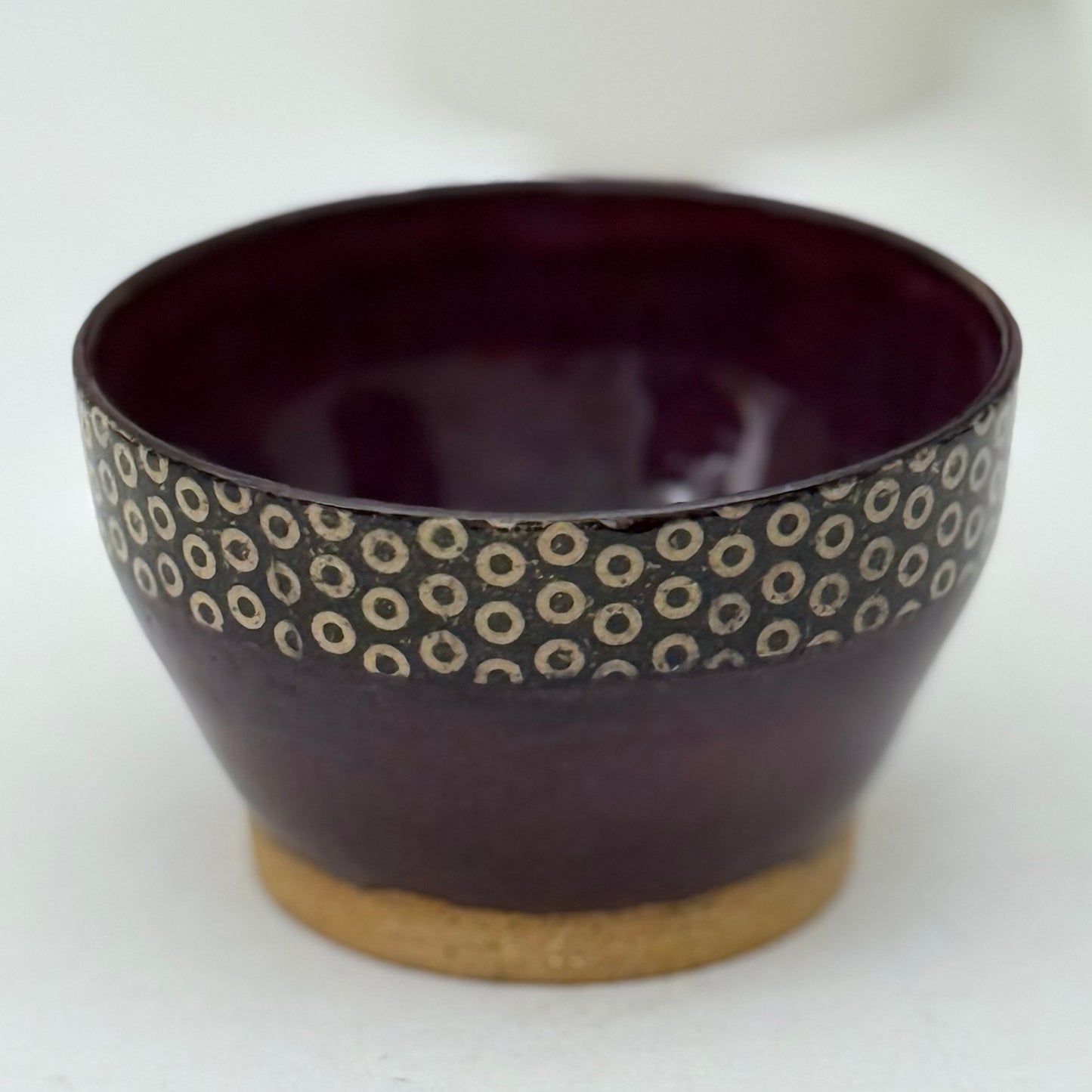 Purple ceramic bowl with circular pattern on a white background