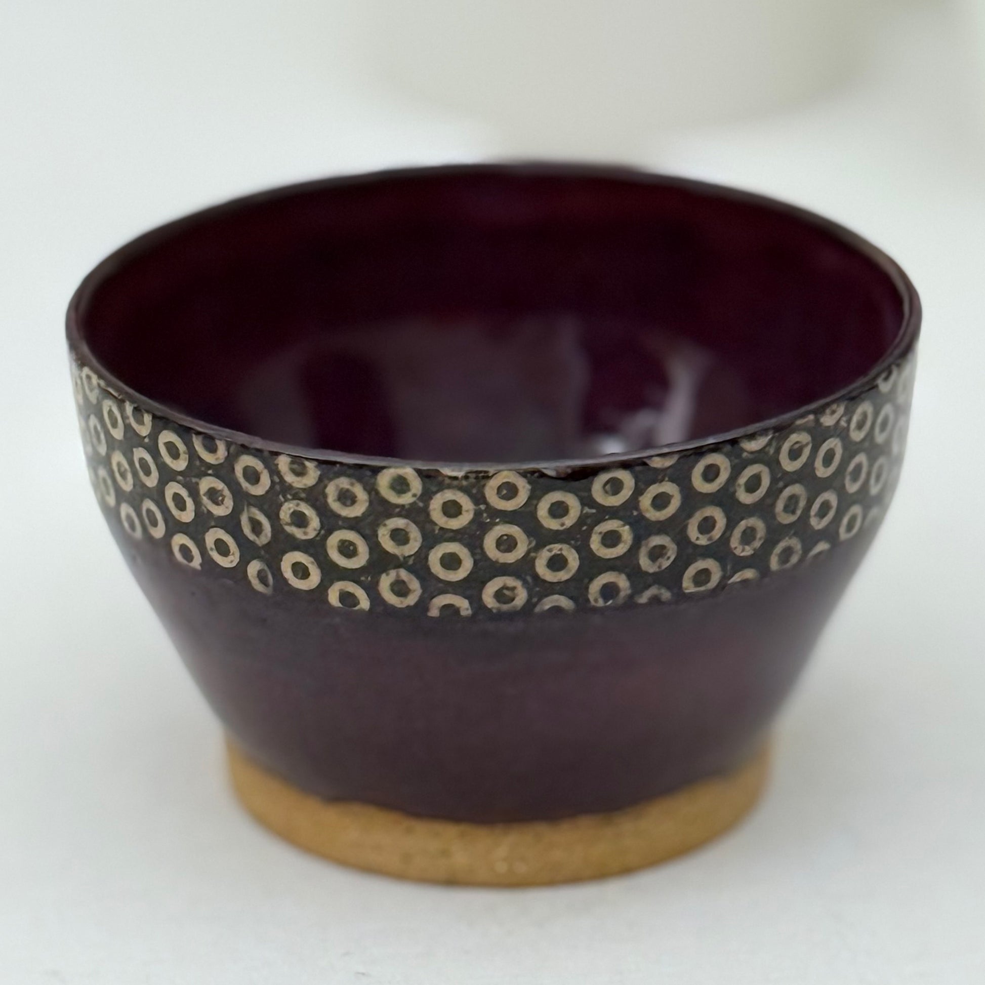 Purple ceramic bowl with circular pattern on a white background