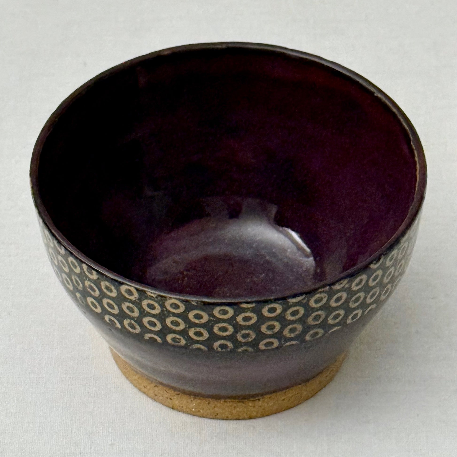 Purple ceramic bowl with circular pattern on a white background