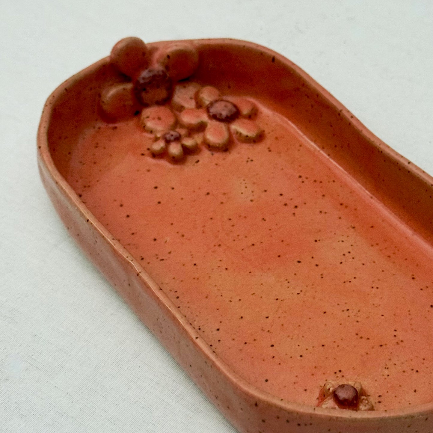 Pink ceramic dish with floral design on a white surface