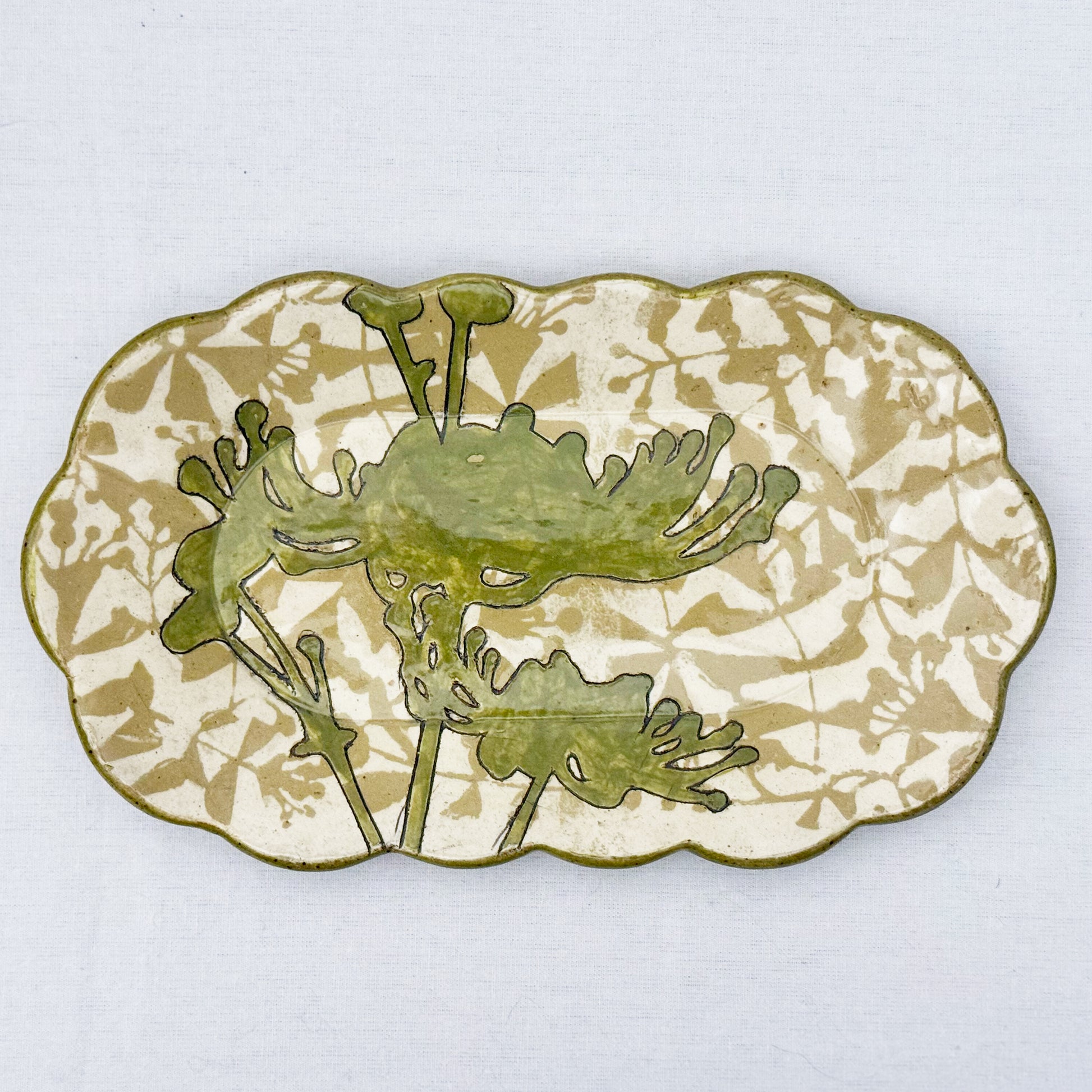 Decorative ceramic plate with olive green floral design on a beige and brown patterned background