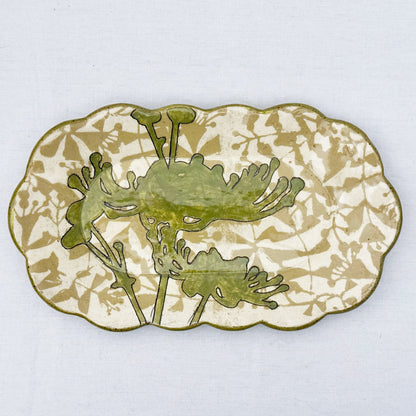 Decorative ceramic plate with olive green floral design on a beige and brown patterned background