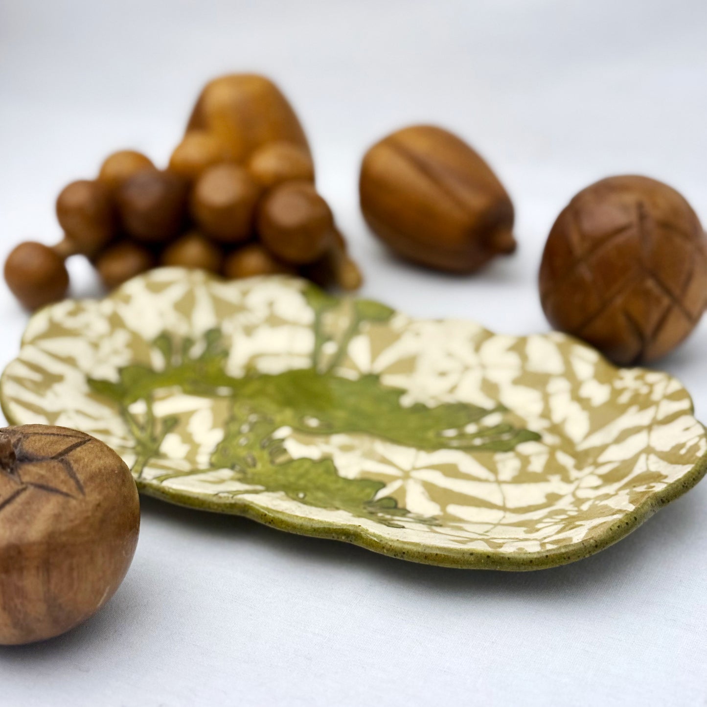 Decorative ceramic plate with olive green floral design on a beige and brown patterned background