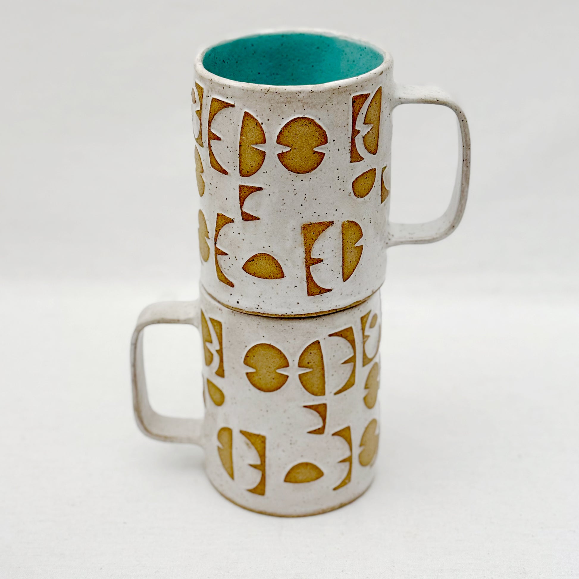 Stack of two ceramic mugs with geometric pattern on a white background