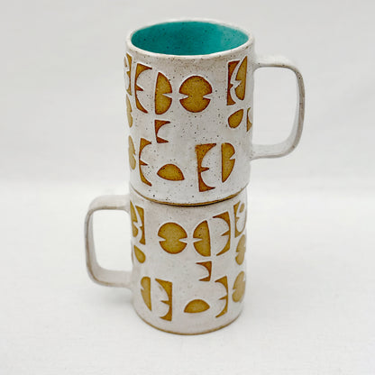 Stack of two ceramic mugs with geometric pattern on a white background