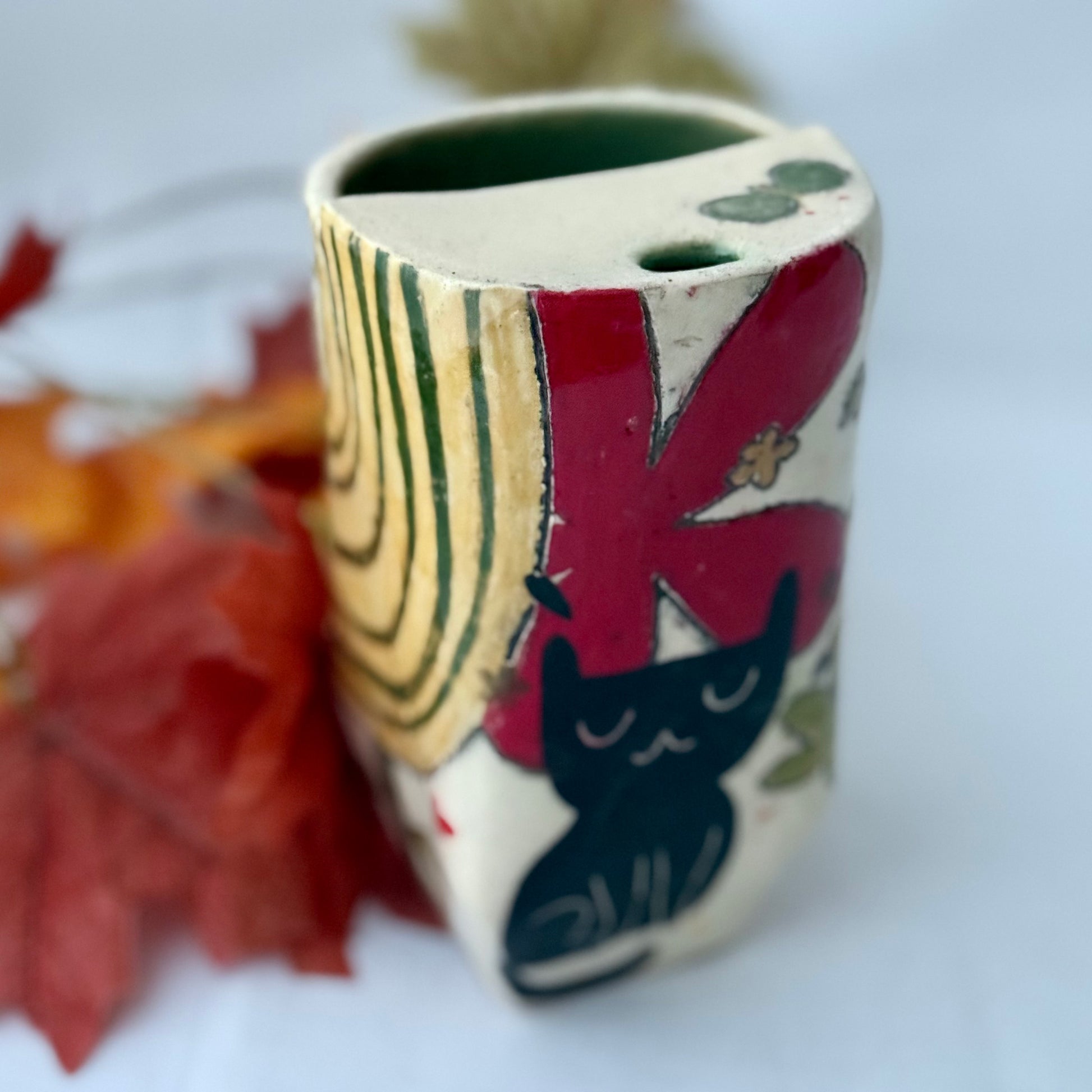 ceramic to go tumbler with flower and cat design on light background with leaves
