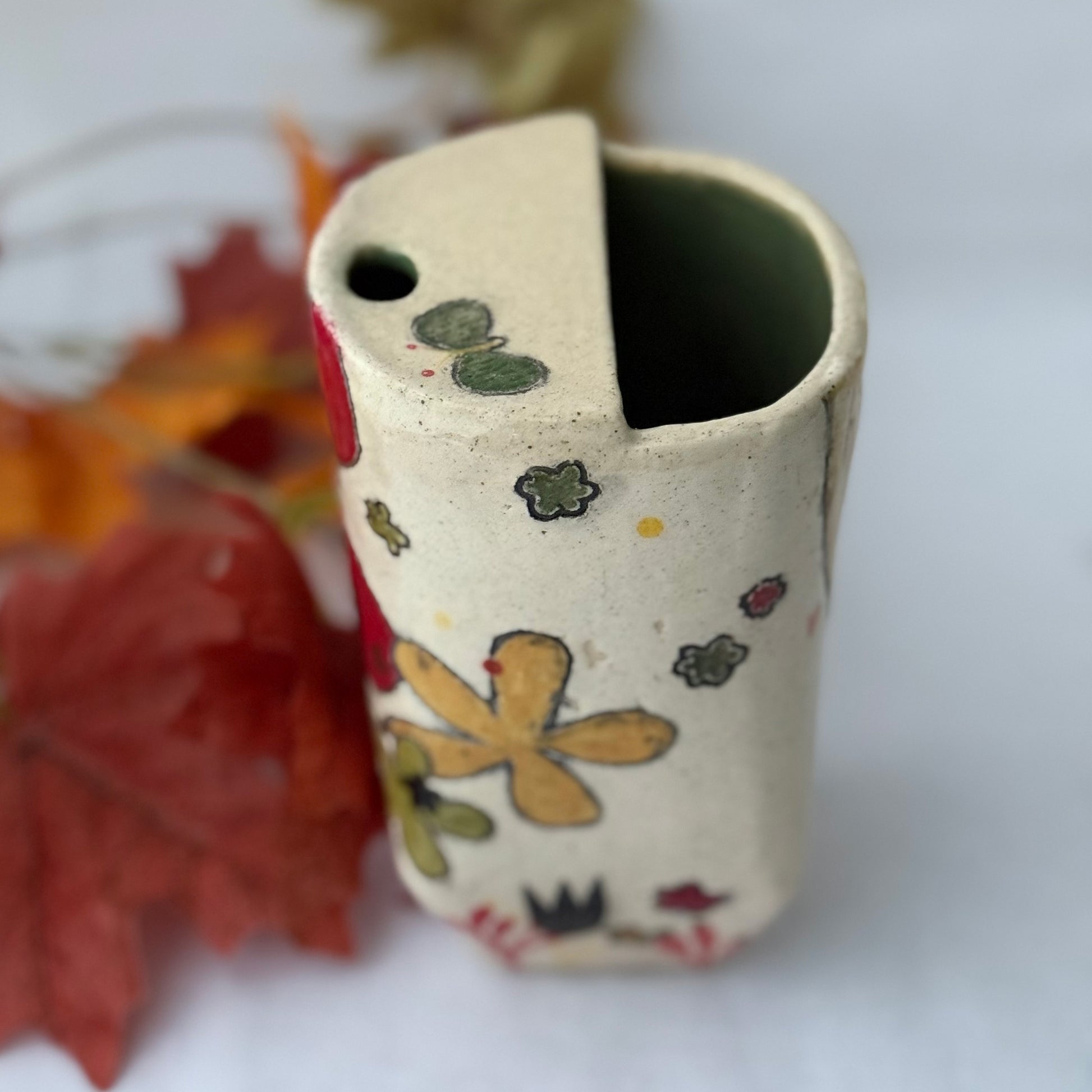 ceramic to go tumbler with flower and cat design on light background with leaves