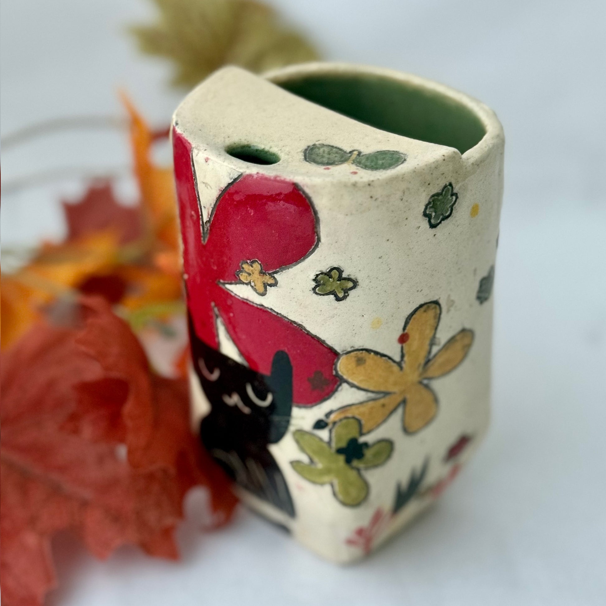 ceramic to go tumbler with flower and cat design on light background with leaves