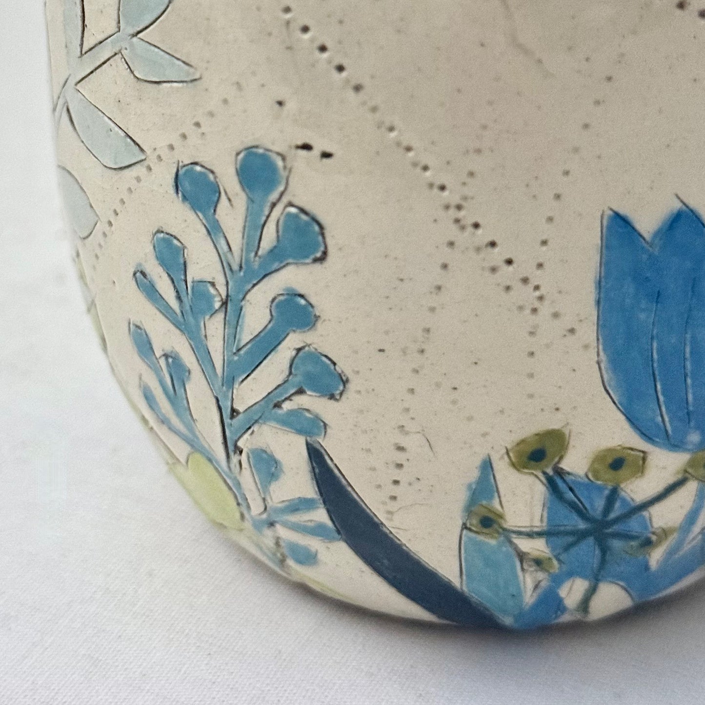 Ceramic mug with blue  and green floral design on a white surface