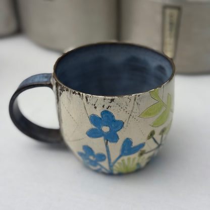 Ceramic mug with blue  and green floral design on a white surface